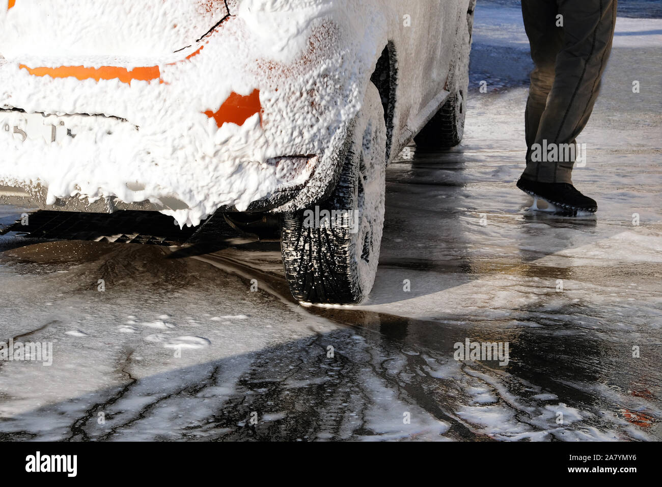 Auto è la pulizia con schiuma di sapone al self-service car wash. White schiuma di sapone su auto. Acqua saponata scorre verso il basso. Foto Stock