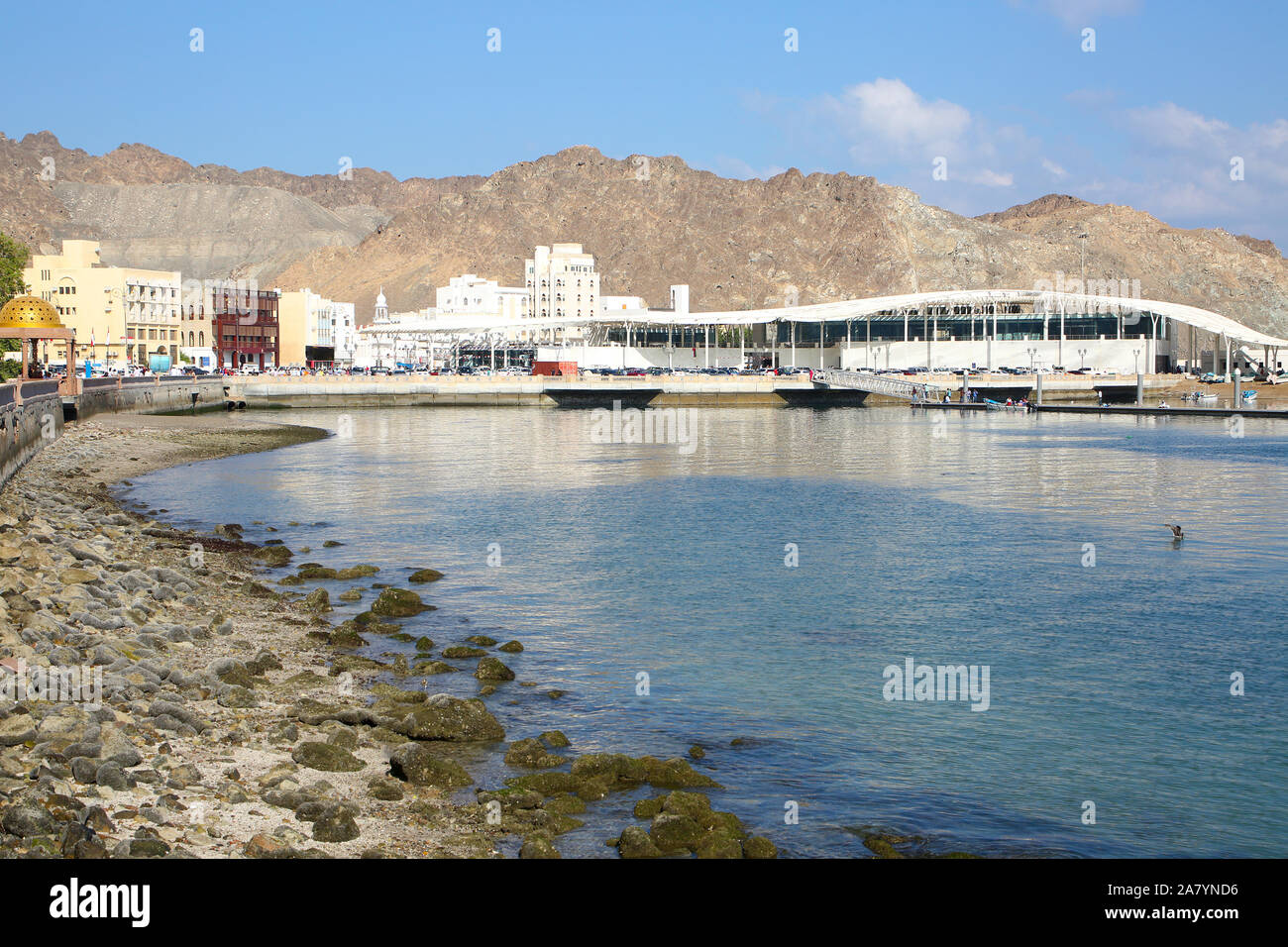 Lungomare della città di Muscat Oman, con edifici in primo piano e circondato da montagne dietro. Foto Stock