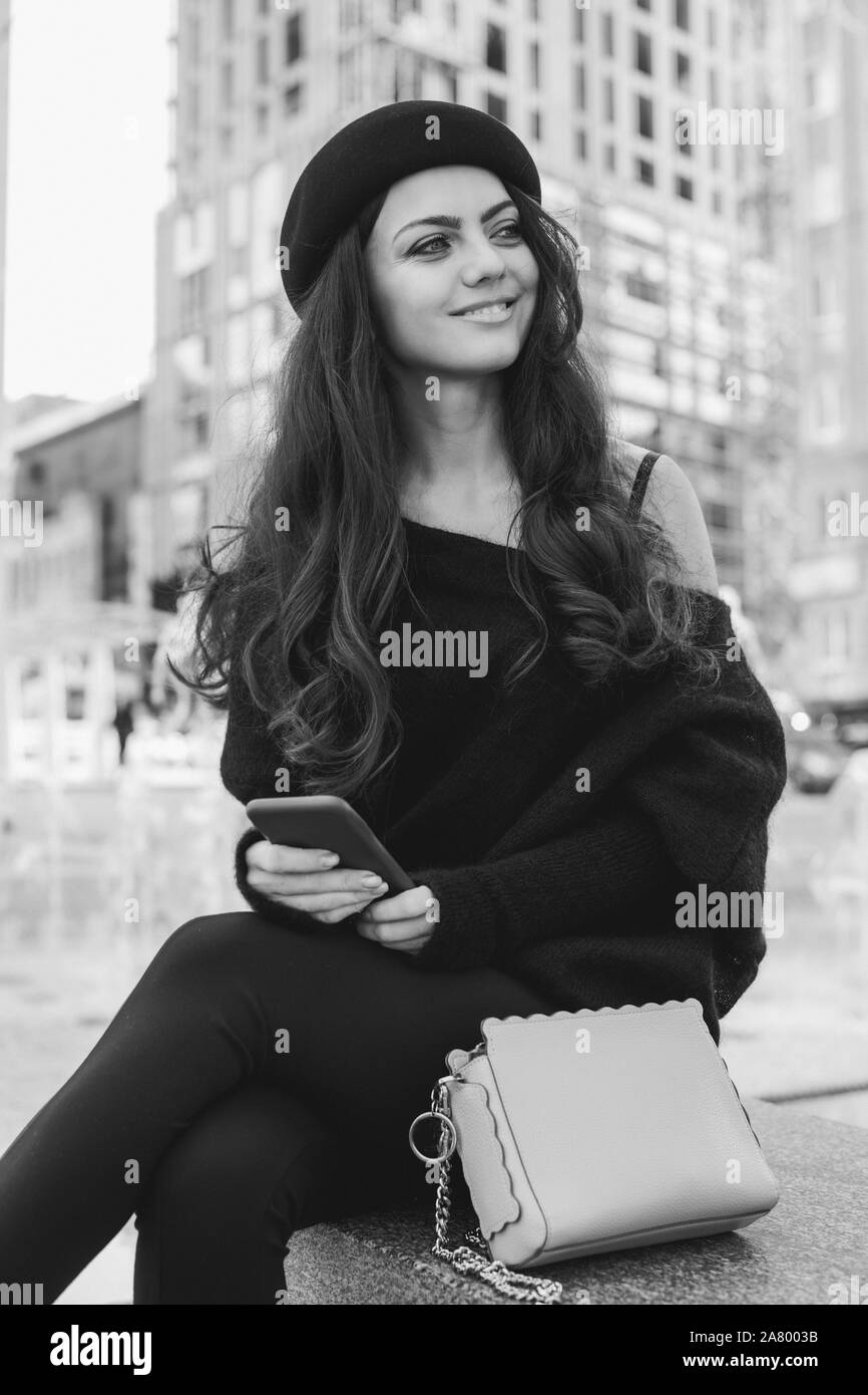 Bella bruna donna vestita in stile retrò utilizza lo smartphone. in bianco e nero Foto Stock