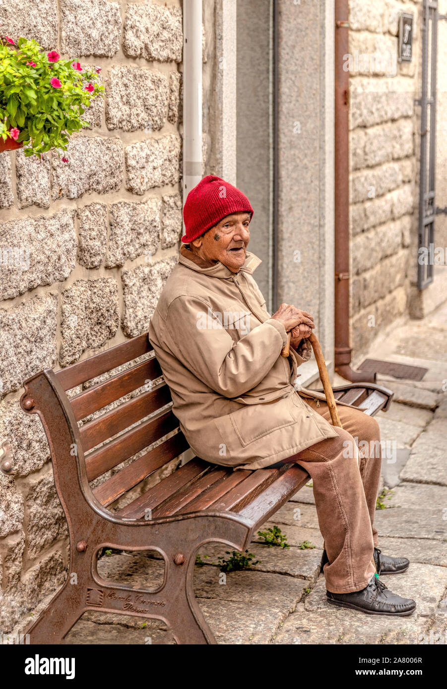 Ritratto di strada di un uomo anziano in una maglia di Red Hat Tempio Pausania, Sassari, Sardegna, Italia. Foto Stock