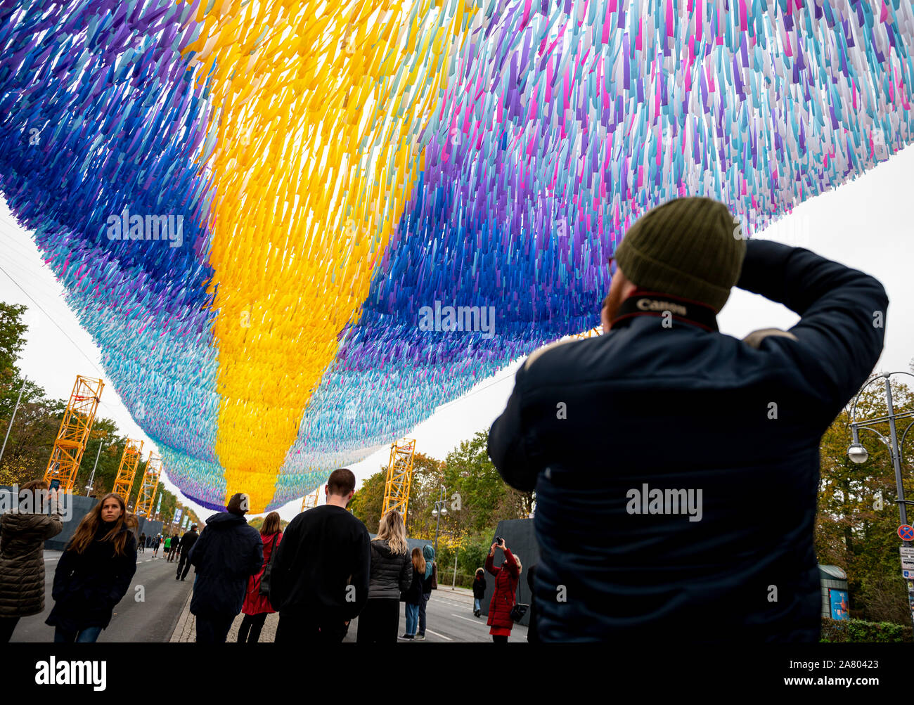 Berlino, Germania. 05 Nov, 2019. Un visitatore di fotografie di arte di installazione 'Visioni in movimento" dell'artista americano Patrick Shearn sulla Strasse des 17. Juni davanti alla Porta di Brandeburgo. Poiché 04.11.2019 i festeggiamenti per l'anniversario della caduta del muro sono in esecuzione. Credito: Fabian Sommer/dpa/Alamy Live News Foto Stock