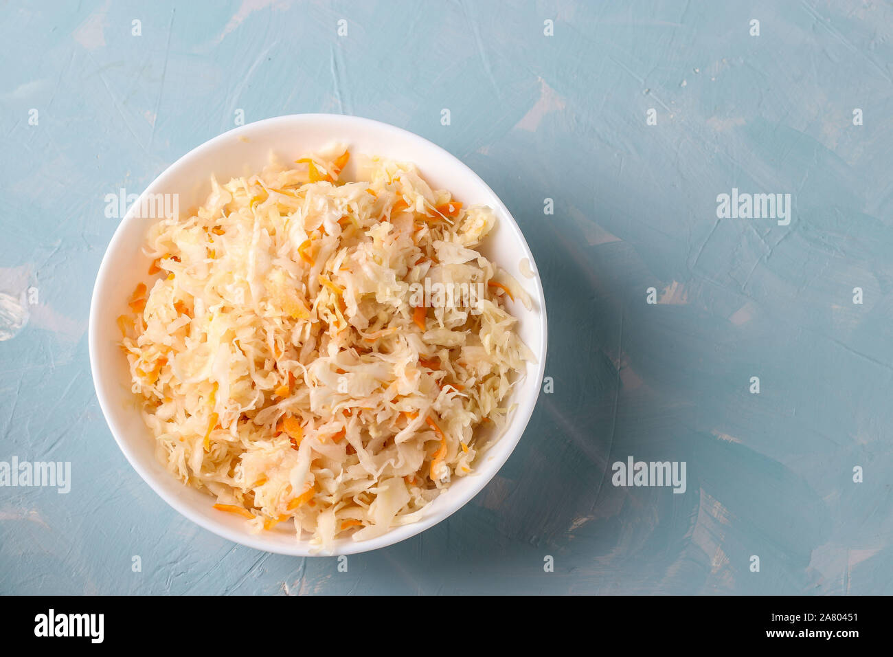 Crauti fatti in casa con le carote in una ciotola su un fondo azzurro, alimento fermentato, vista dall'alto Foto Stock