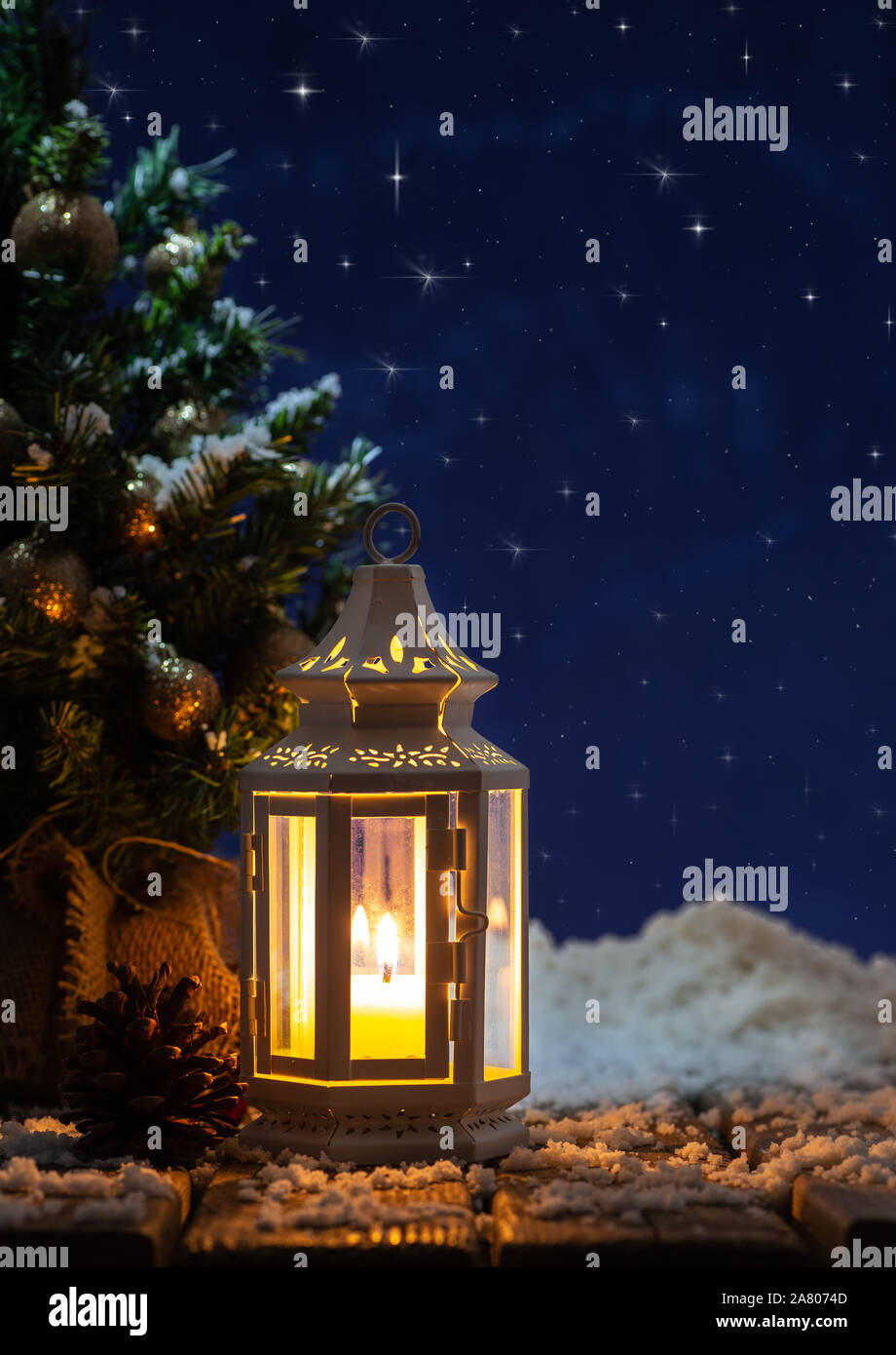 Vacanze inverno scena di una lanterna incandescente e albero di Natale contro un cielo notturno con brillanti stelle brillanti Foto Stock