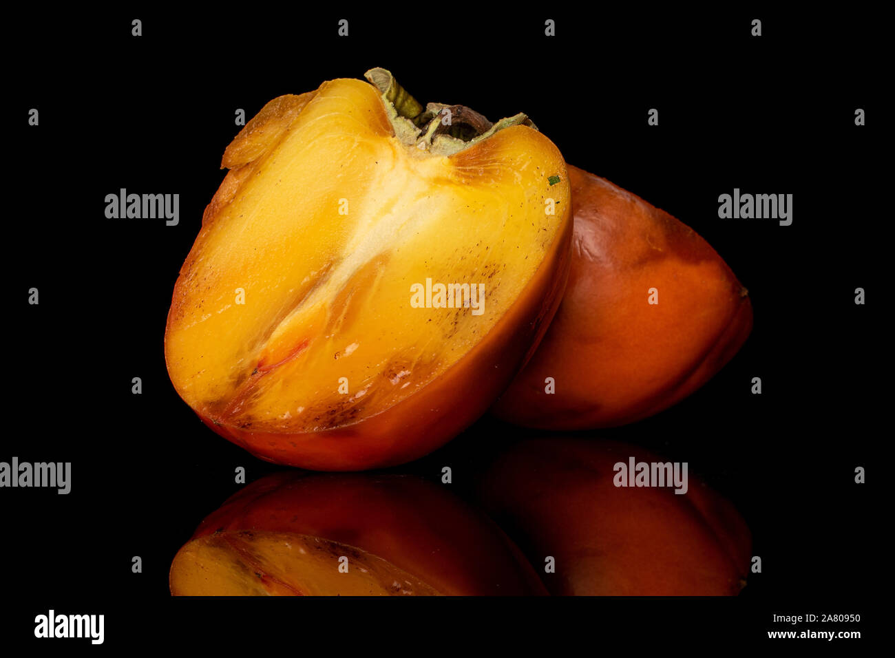 Gruppo di due metà di arancio dolce persimmon isolato sul vetro nero Foto Stock