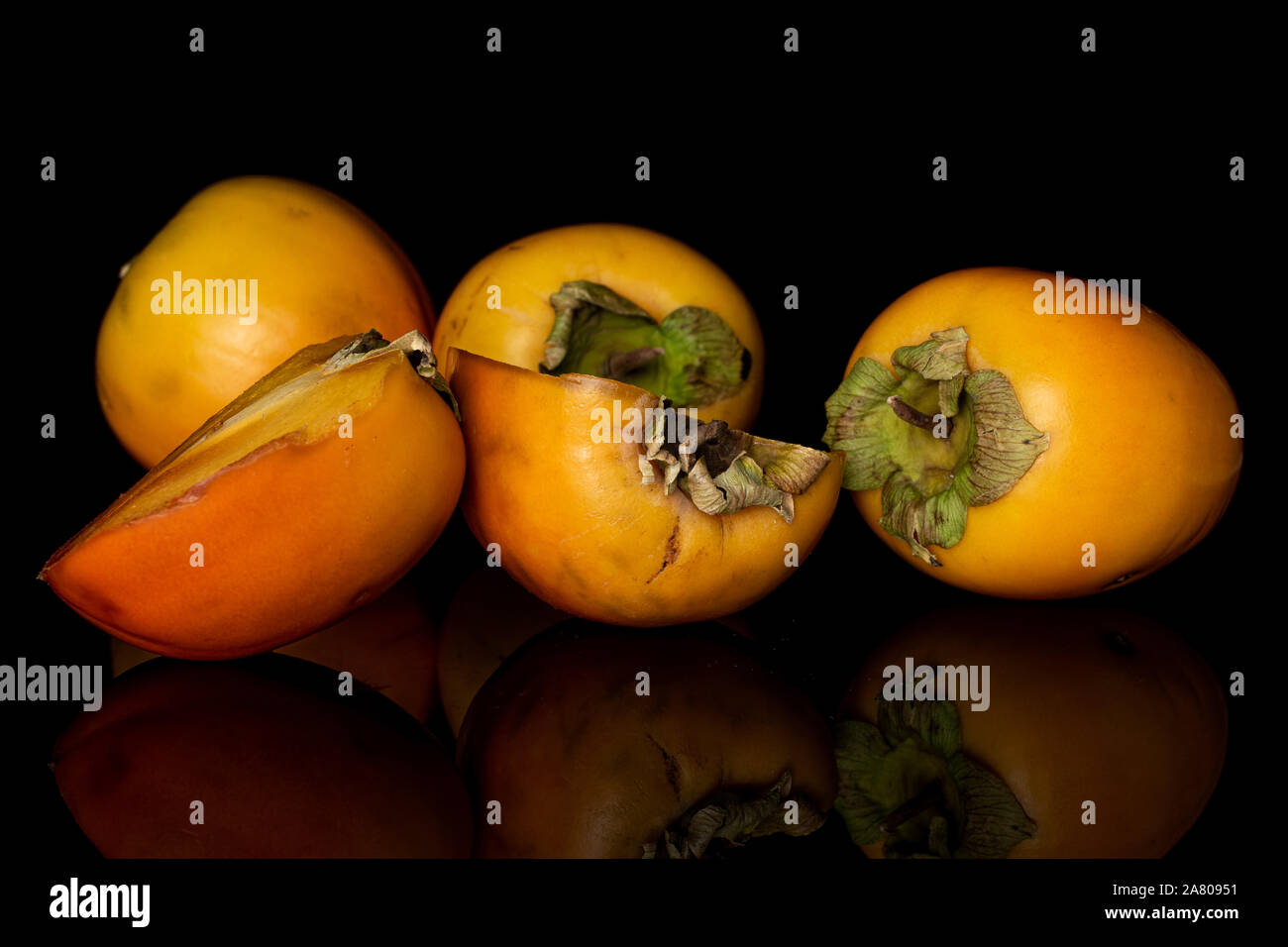 Gruppo di tre insieme due metà di arancio dolce persimmon isolato sul vetro nero Foto Stock
