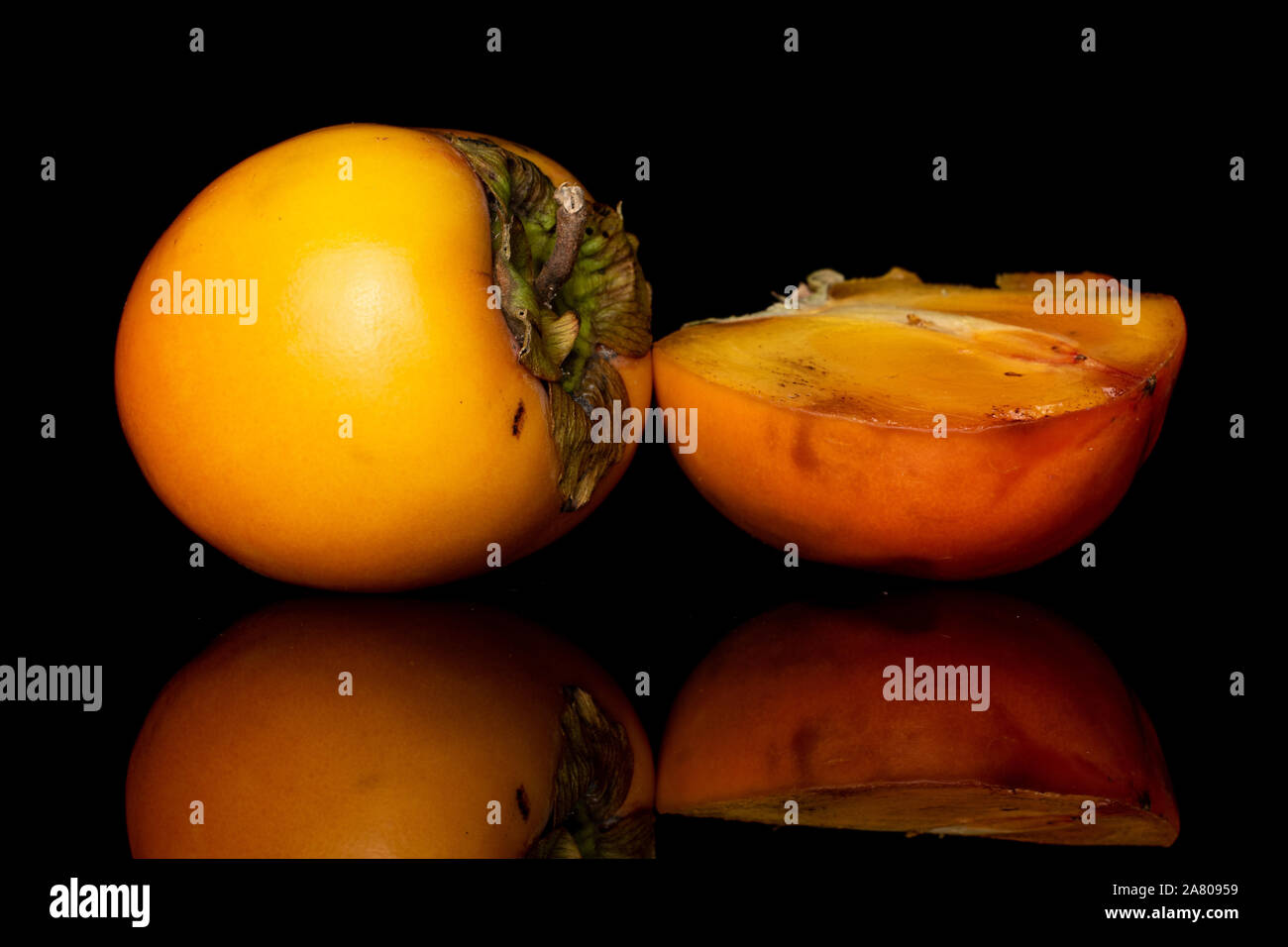 Gruppo di una intera metà di arancio dolce persimmon isolato sul vetro nero Foto Stock