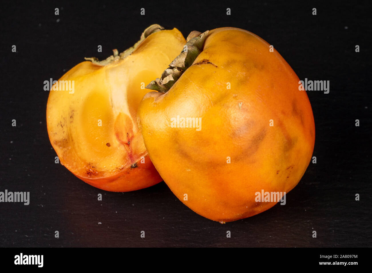Gruppo di due metà di arancio dolce persimmon sulla pietra grigia Foto Stock