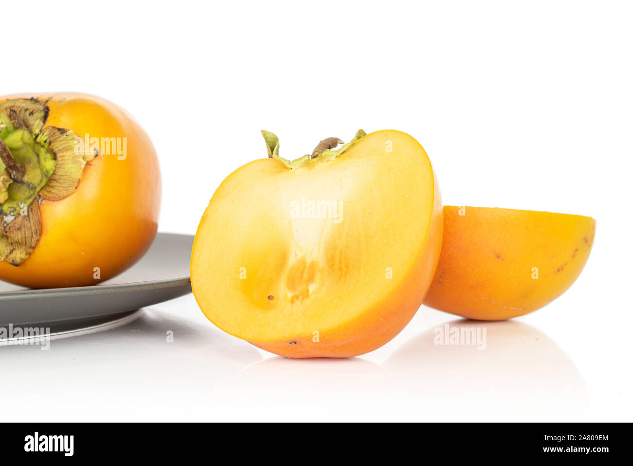 Gruppo di una intera due metà di arancio dolce persimmon grigio su piastra in ceramica isolata su sfondo bianco Foto Stock
