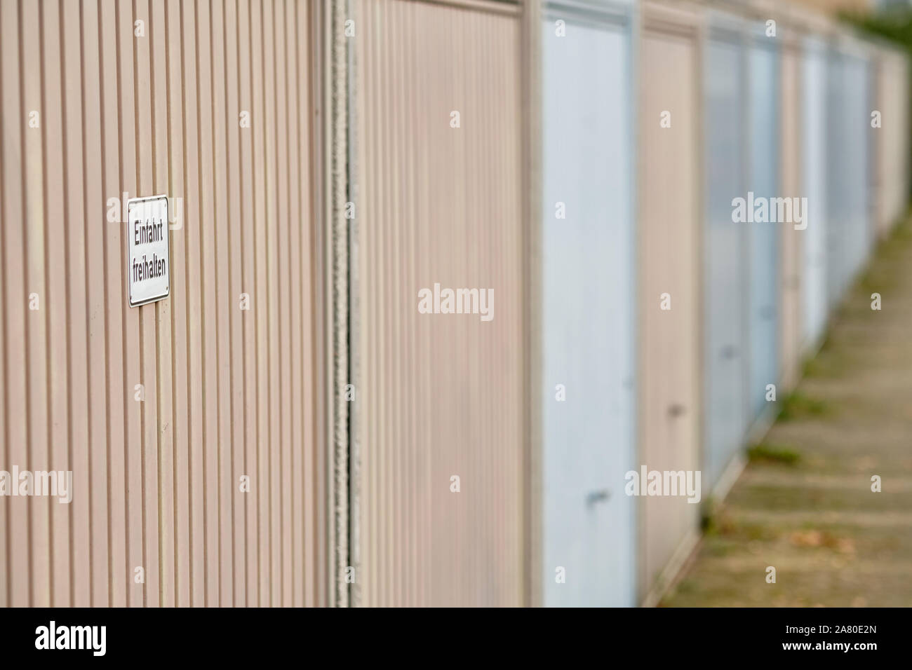Fila di porte di garage con un segno sulla prima porta che dice ' Einfahrt freihalten ' (in inglese: tenere il passo carraio clear ). Visto in Germania nel mese di novembre. Foto Stock