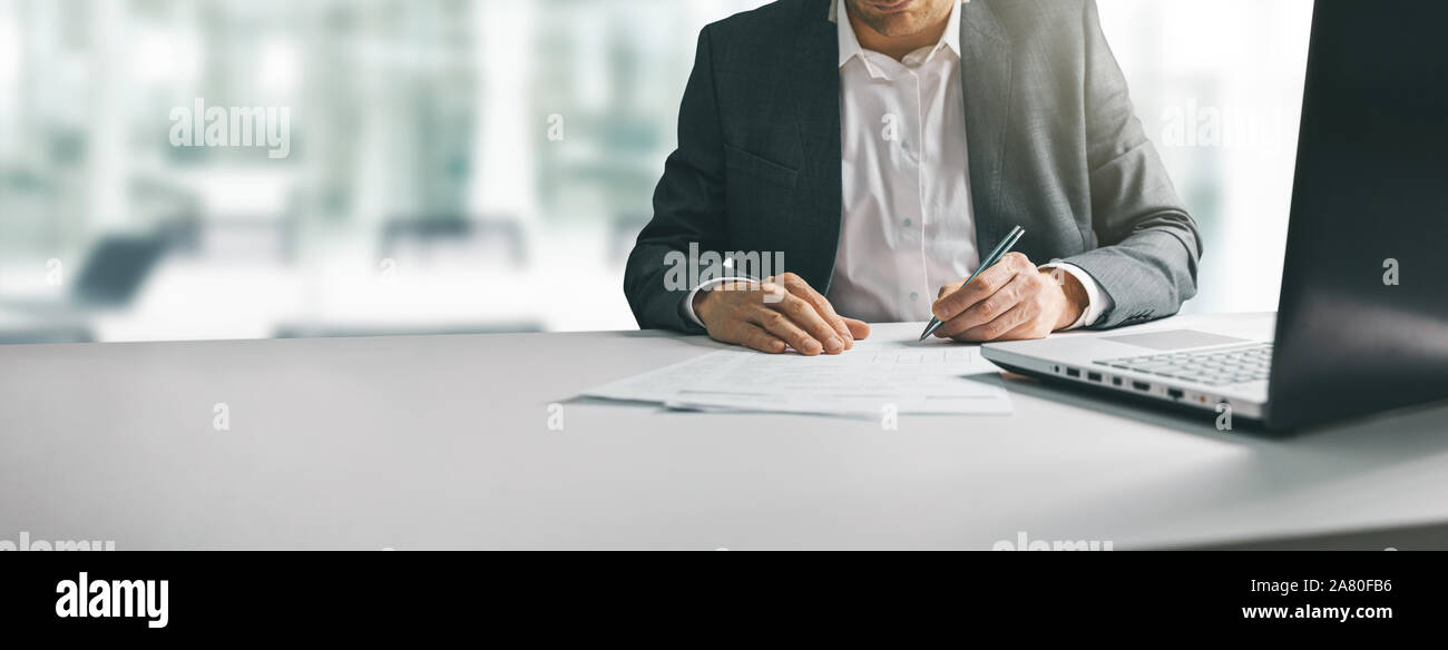 Giovane uomo in tuta la scrittura di documenti aziendali al banco nel moderno ufficio coworking. spazio copia Foto Stock