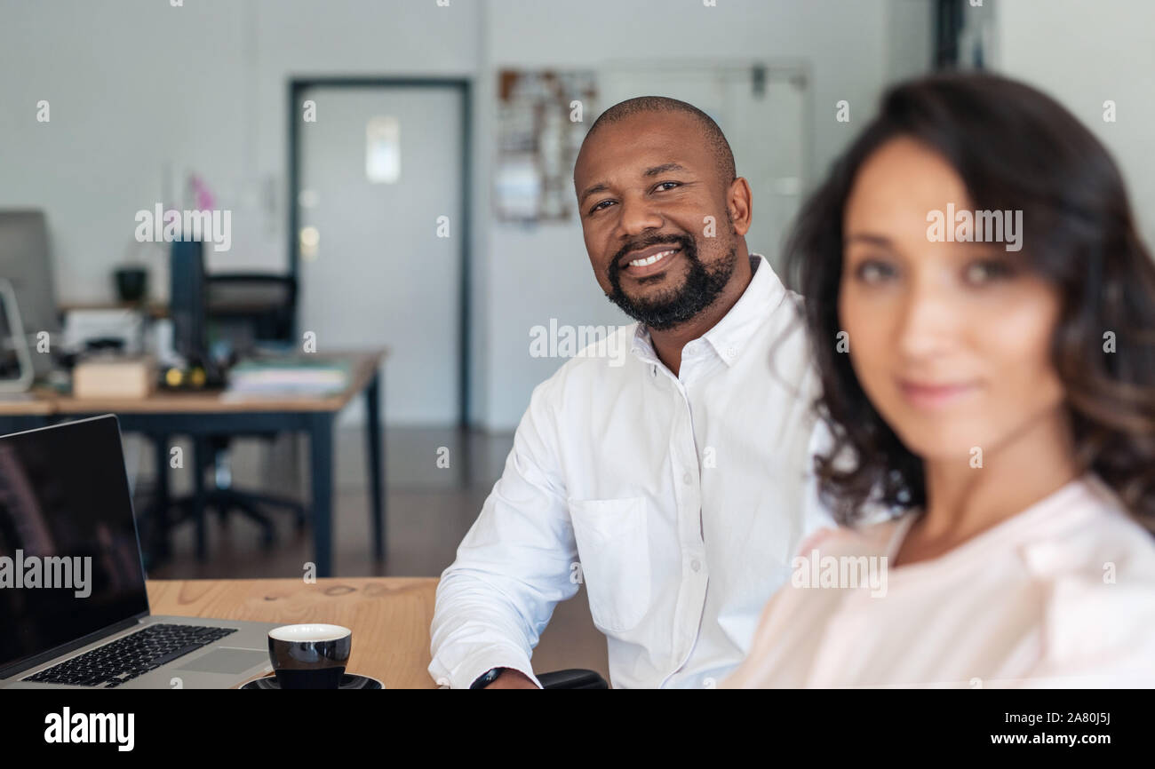 Imprenditore sorridente seduto con un collega in un ufficio Foto Stock
