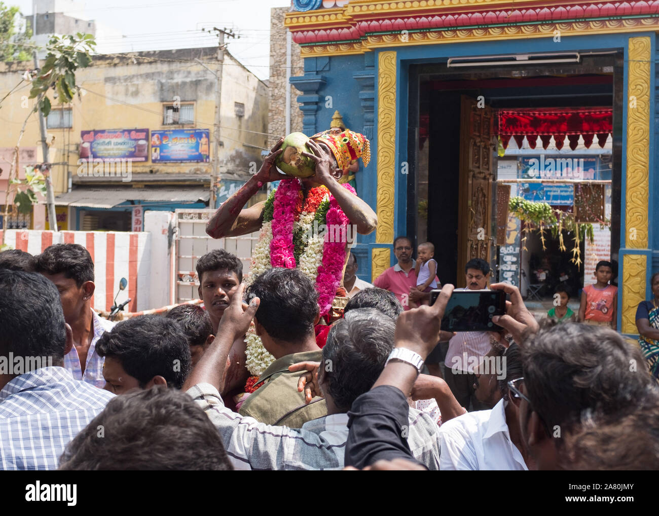 Sacerdote sulle spalle dei devoti di bere il sangue di un sacrificati giovane capra durante Kutti Kudithal Festival di Trichy, Tamil Nadu, India Foto Stock