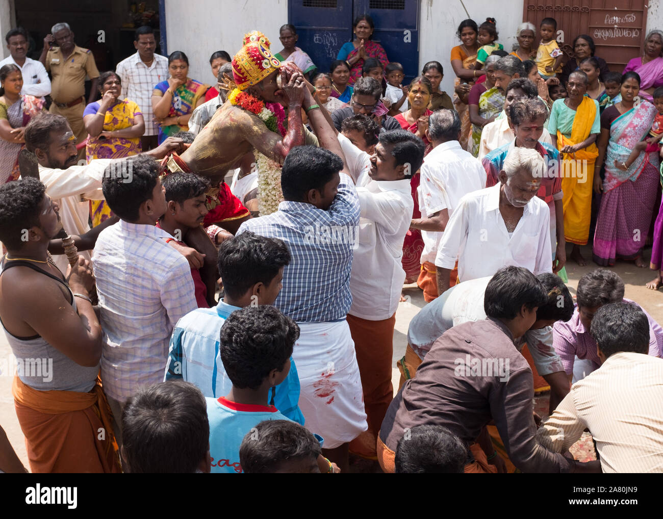 Sacerdote sulle spalle dei devoti di bere il sangue di un sacrificati giovane capra durante Kutti Kudithal Festival di Trichy, Tamil Nadu, India Foto Stock