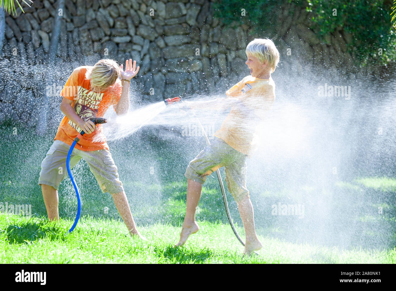 Fratelli giocando con giardino hosepipes Foto Stock