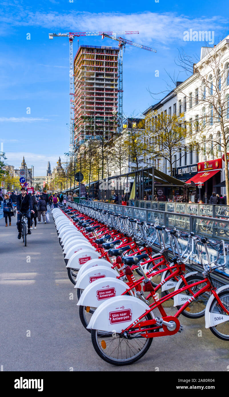 Linea di city bike per noleggio - "Velo Antwerpen' - e la torre di Anversa la ricostruzione di edifici - Anversa, Belgio. Foto Stock