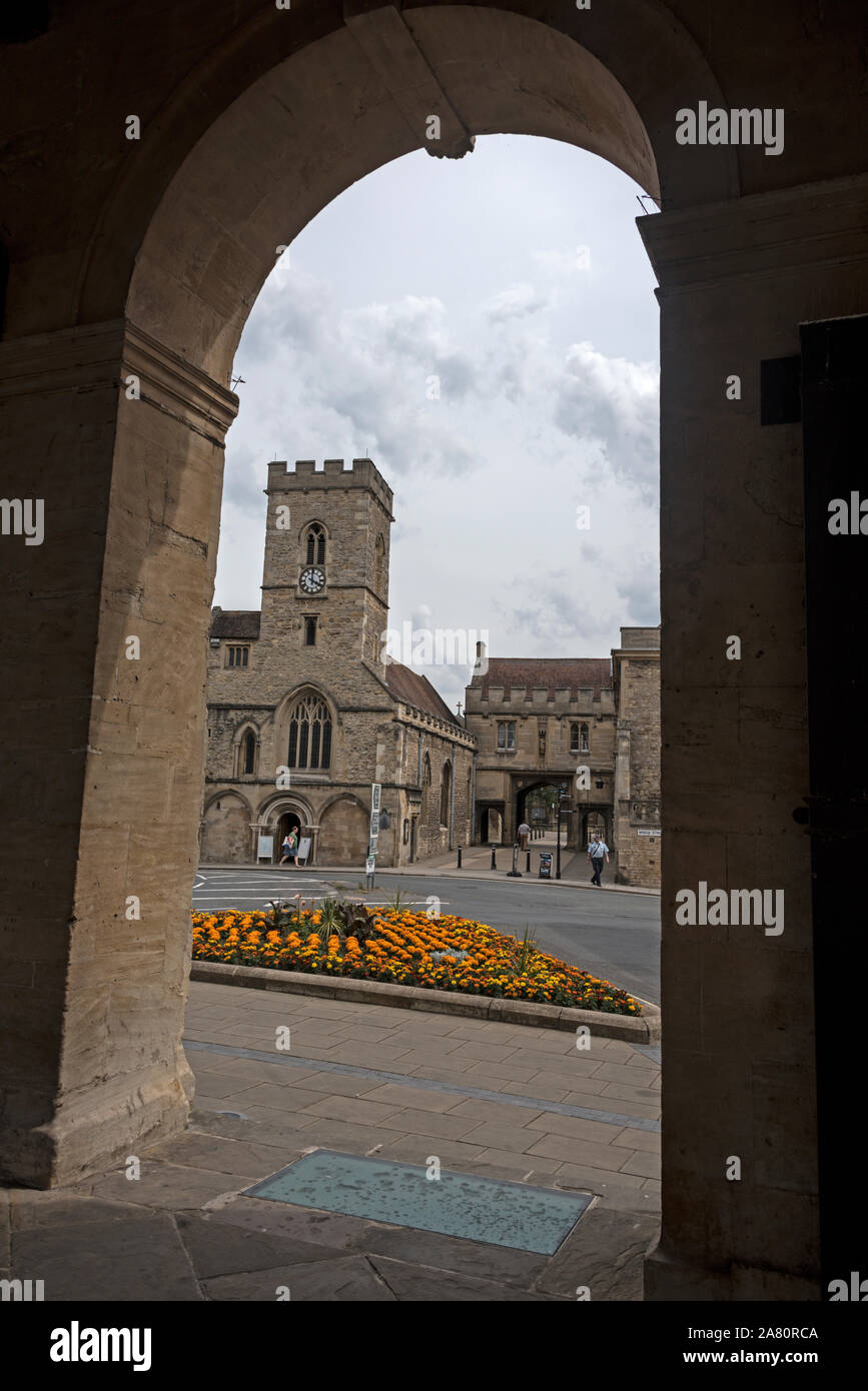 Attraverso il grande arco di Abingdon County Hall Museum verso Saint NicolasÕ chiesa e la Guild Hall in Abingdon-on-Thames, un mercato storico di Foto Stock
