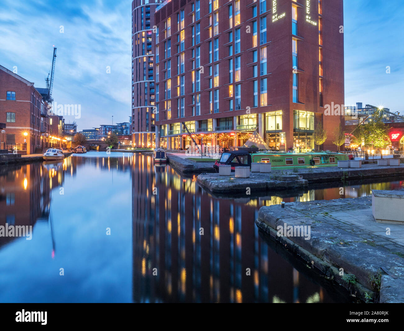 Hotel moderno di riflessione nel canal al tramonto a Granary Wharf Leeds West Yorkshire Inghilterra Foto Stock