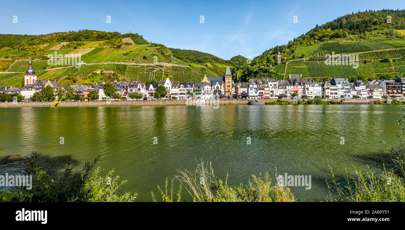 Panorama della comunità Zell sul fiume Moselle, Germania, case lungo la riva del fiume con ripidi vigneti e Torre di Collis Foto Stock