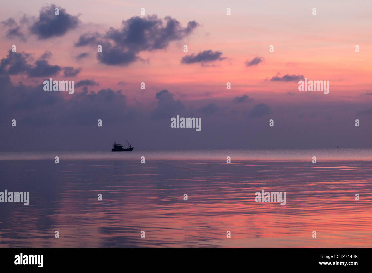 Tranquilla marina all'alba con cielo rosa e distante barca da pesca, Koh Rong isola, Cambogia Foto Stock