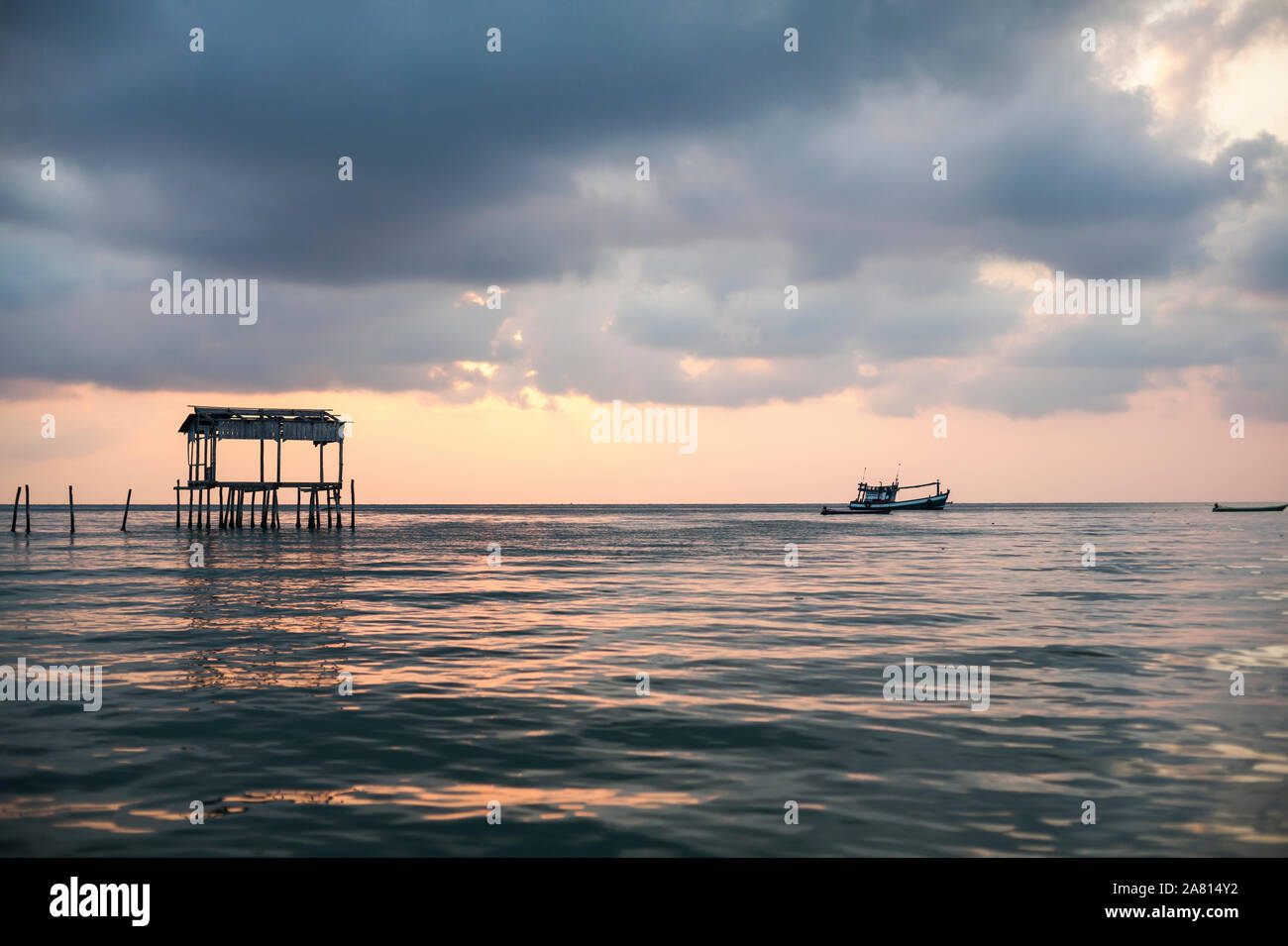 Seascape all'alba con cielo drammatico, vecchio pontile in legno e la barca da pesca all'orizzonte, Koh Rong isola, Cambogia. Foto Stock