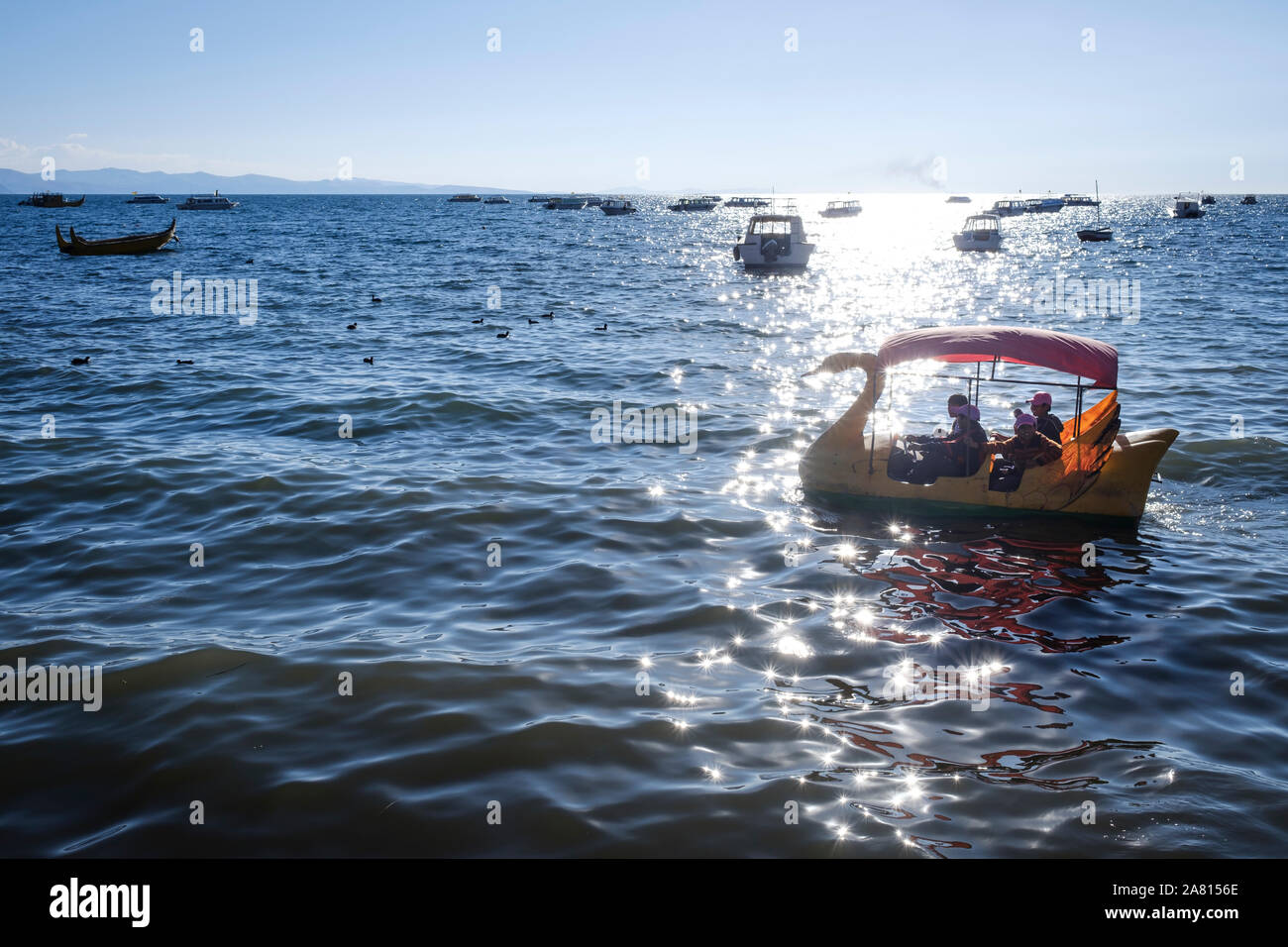 La popolazione locale a cavallo su un anatra a forma di barca in spiaggia di Copacabana, Bolivia Foto Stock