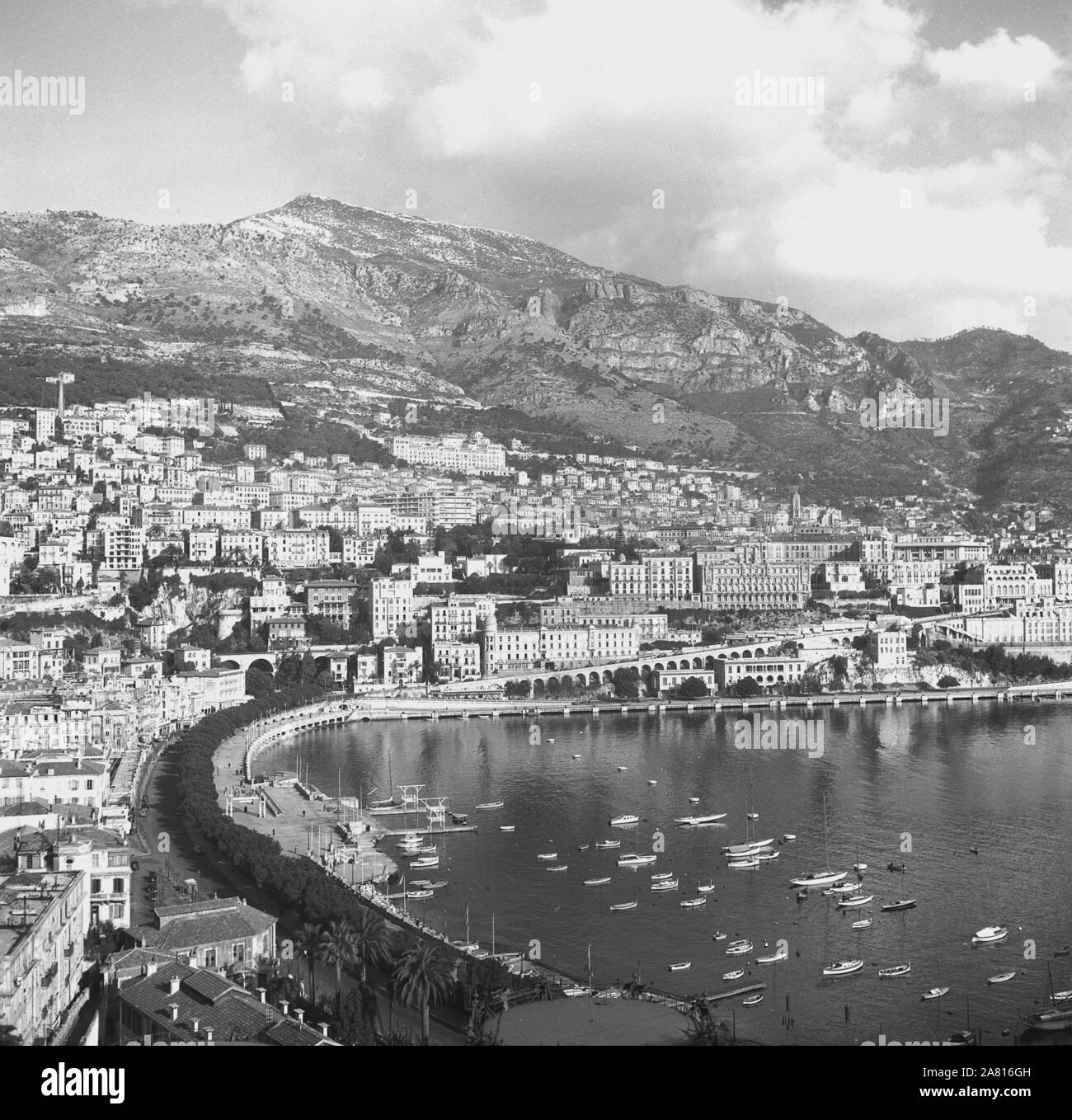 Degli anni Cinquanta, storico, una vista sul porto di Monaco, che mostra gli edifici del famoso Monte Carlo district costruito sul fianco di una collina del francese Rivieria. Foto Stock