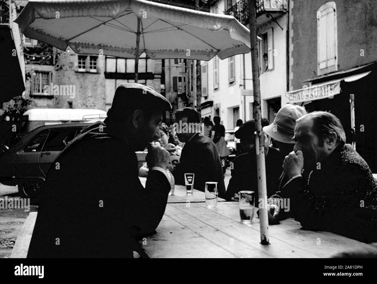 Gli agricoltori locali a bere pastis in piazza, Place du Centre, Coupiac, Aveyron, Occitanie, Francia. Scansione in bianco e nero film negativo, 1968 Foto Stock