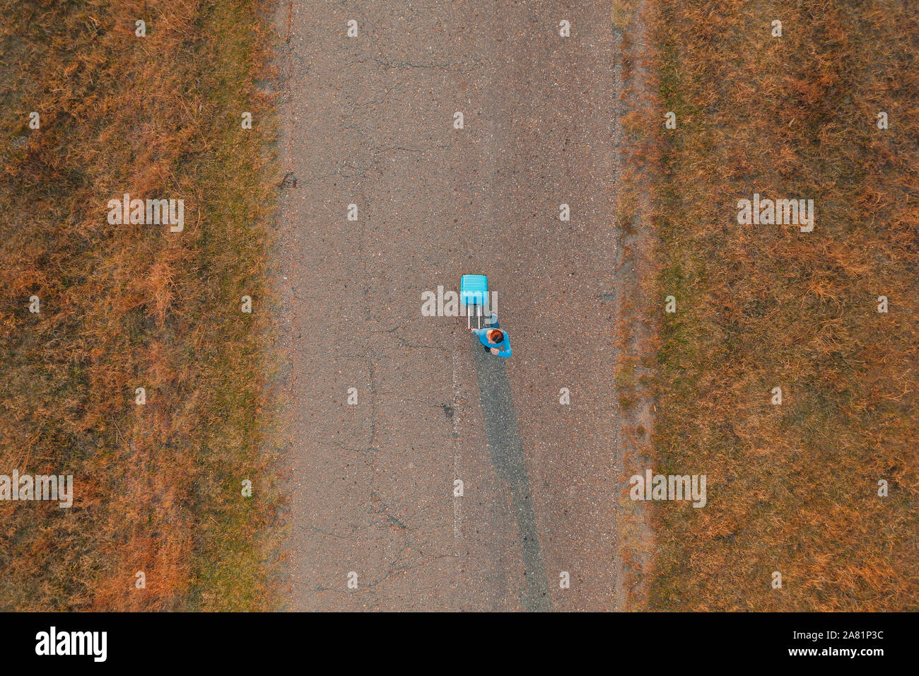 Tirando la donna valigia viaggio bagagli su strada in autunno tramonto, elevato angolo vista da fuco pov Foto Stock