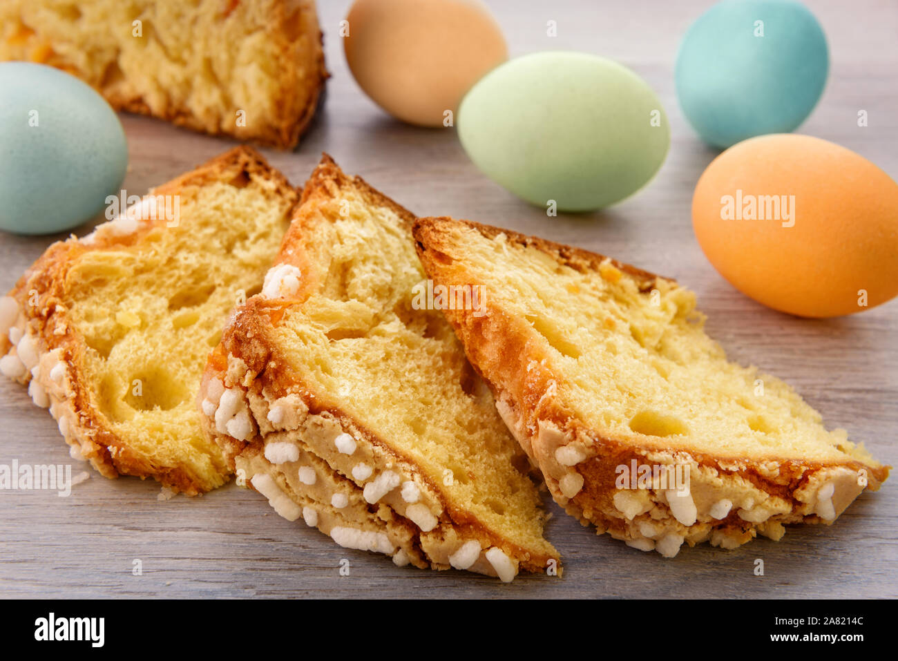 Fette di torta di Pasqua e uova colorate sono su un tavolo di legno alto. Foto Stock