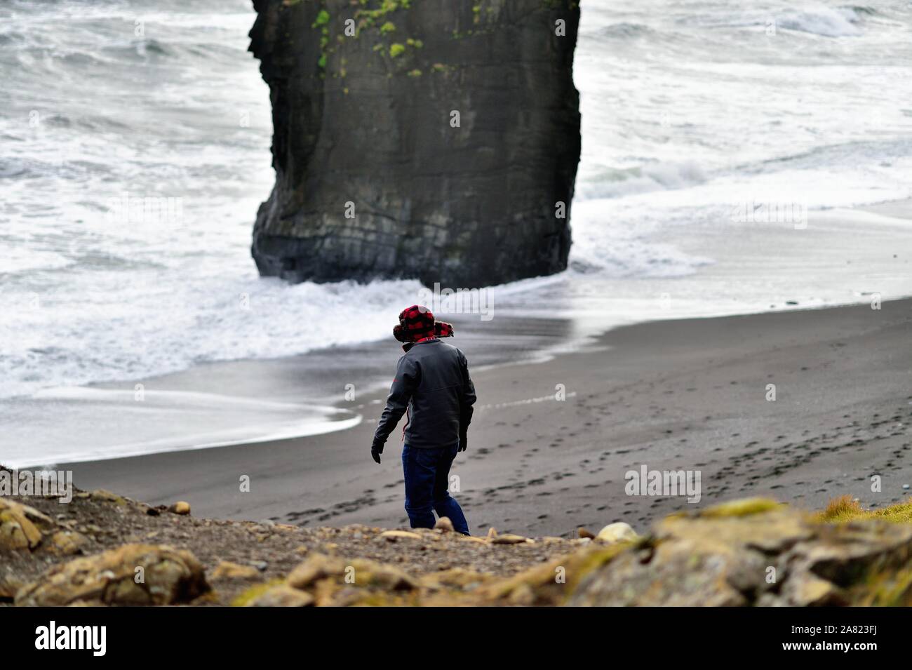 Oriente fiordi, Islanda. Lone visite turistiche di una spiaggia di sabbia nera formata da attività vulcanica lungo l'Islanda Fiordi Orientali. Foto Stock