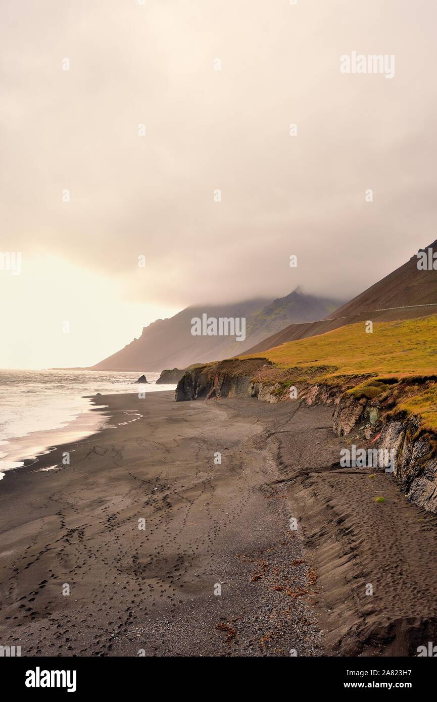Oriente fiordi, Islanda. Rocce e spiagge di sabbia nera formata da attività vulcanica sono spruzzati in Islanda Fiordi Orientali. Foto Stock