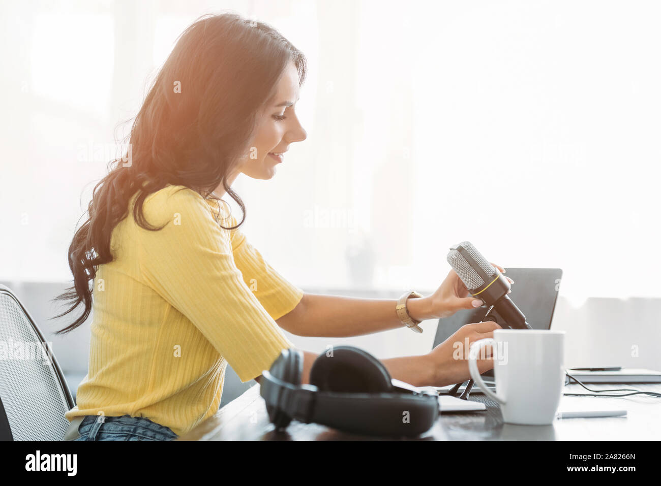 Piuttosto host radio regolazione microfono mentre è seduto al posto di lavoro in studio di trasmissione Foto Stock