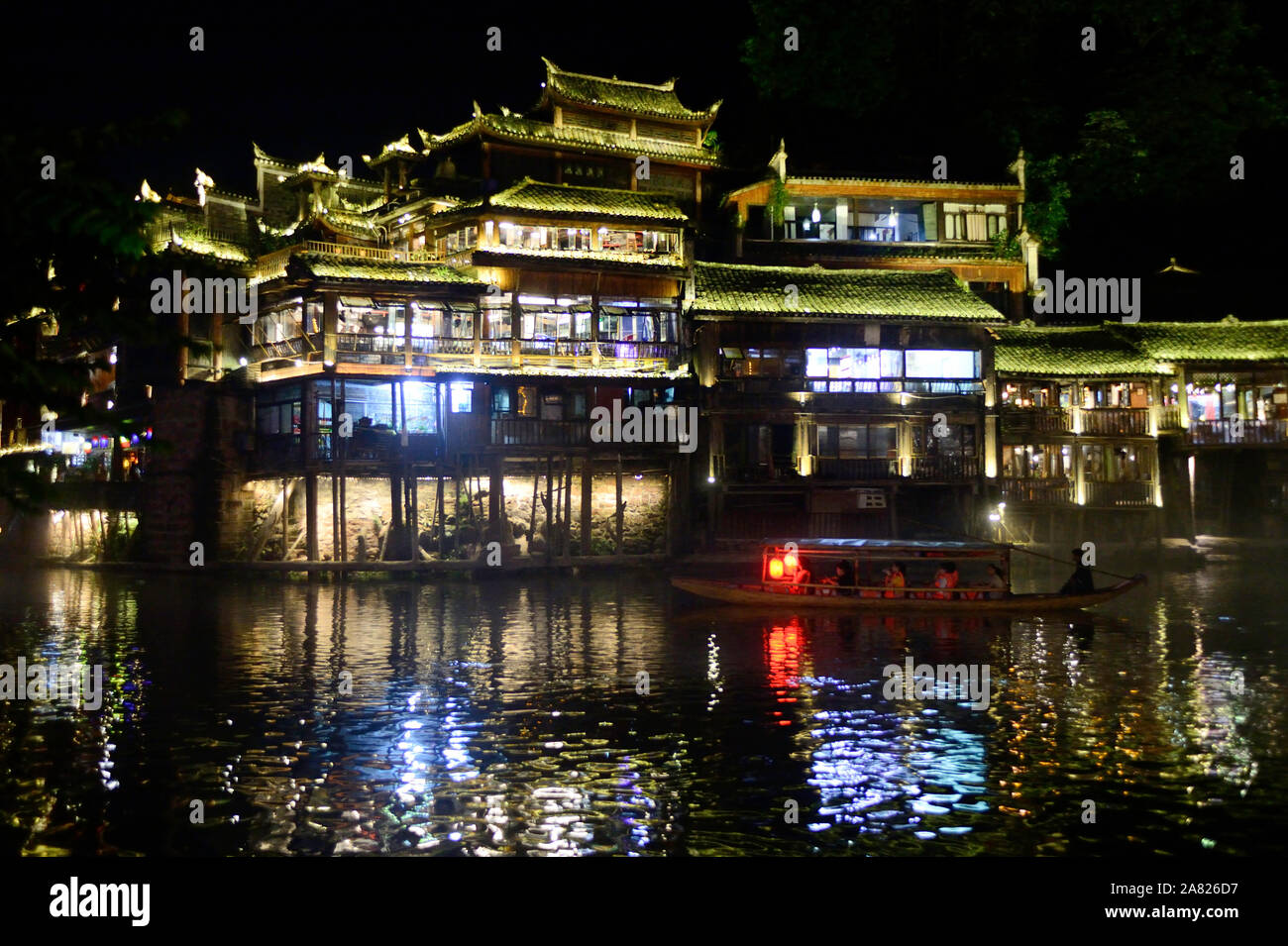 Un Sampan barca porta i turisti attraverso il passaggio di acquosa del Tuo Jiang fiume di notte in Fenghuang antica città in Tibet, in Cina. Foto Stock