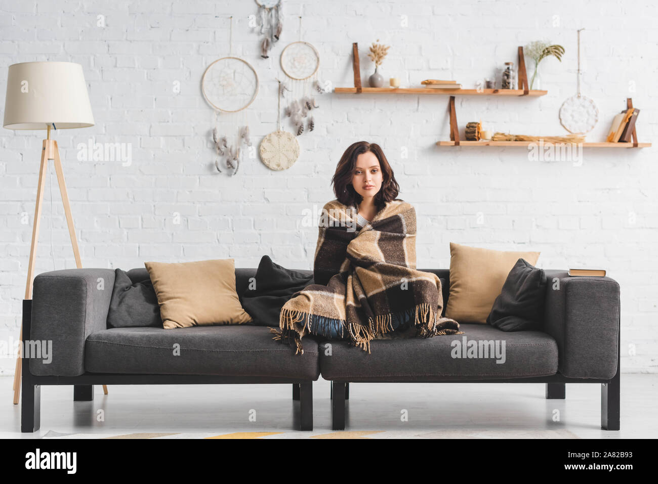 Attraente ragazza a freddo in fase di riscaldamento con un lenzuolo sul  divano nel soggiorno con raccoglitori per sogno Foto stock - Alamy