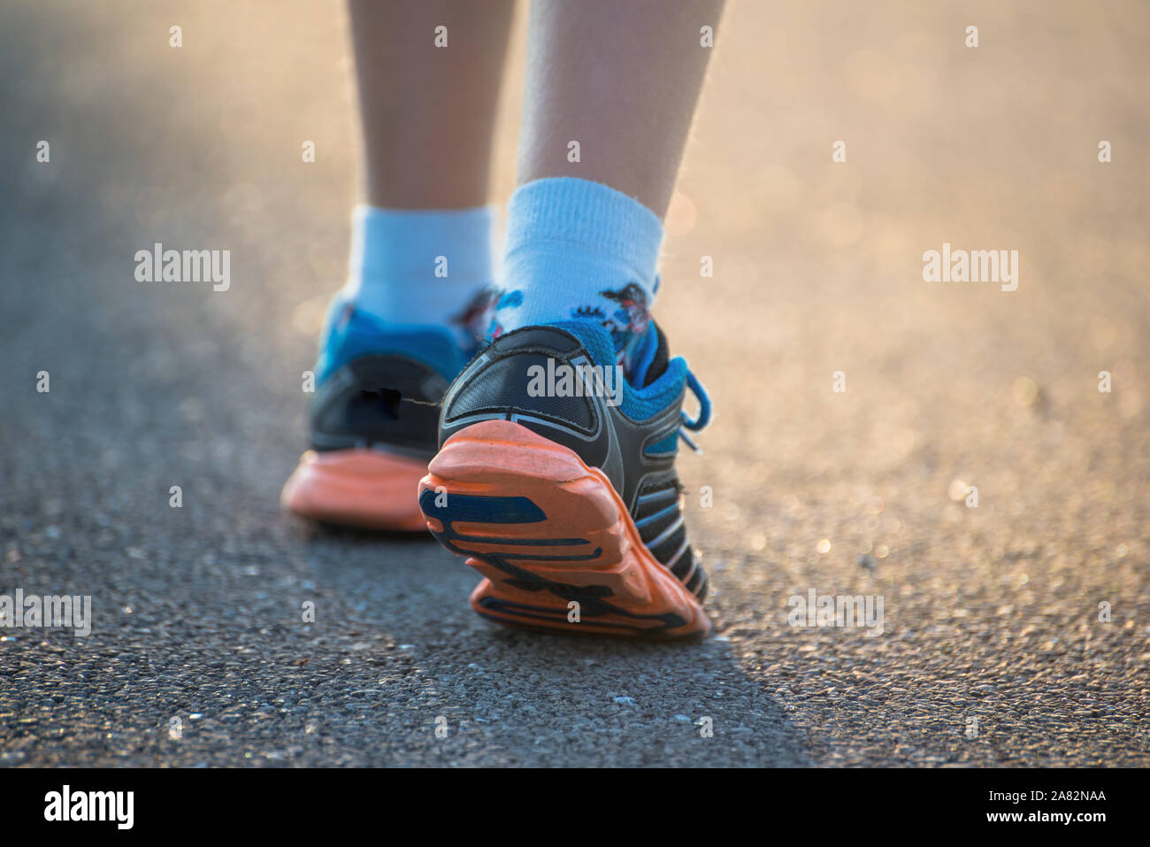 Kid passeggiate, esercitando su di una strada rurale, vicino fino in kids piedi indossando scarpe Palestra Foto Stock