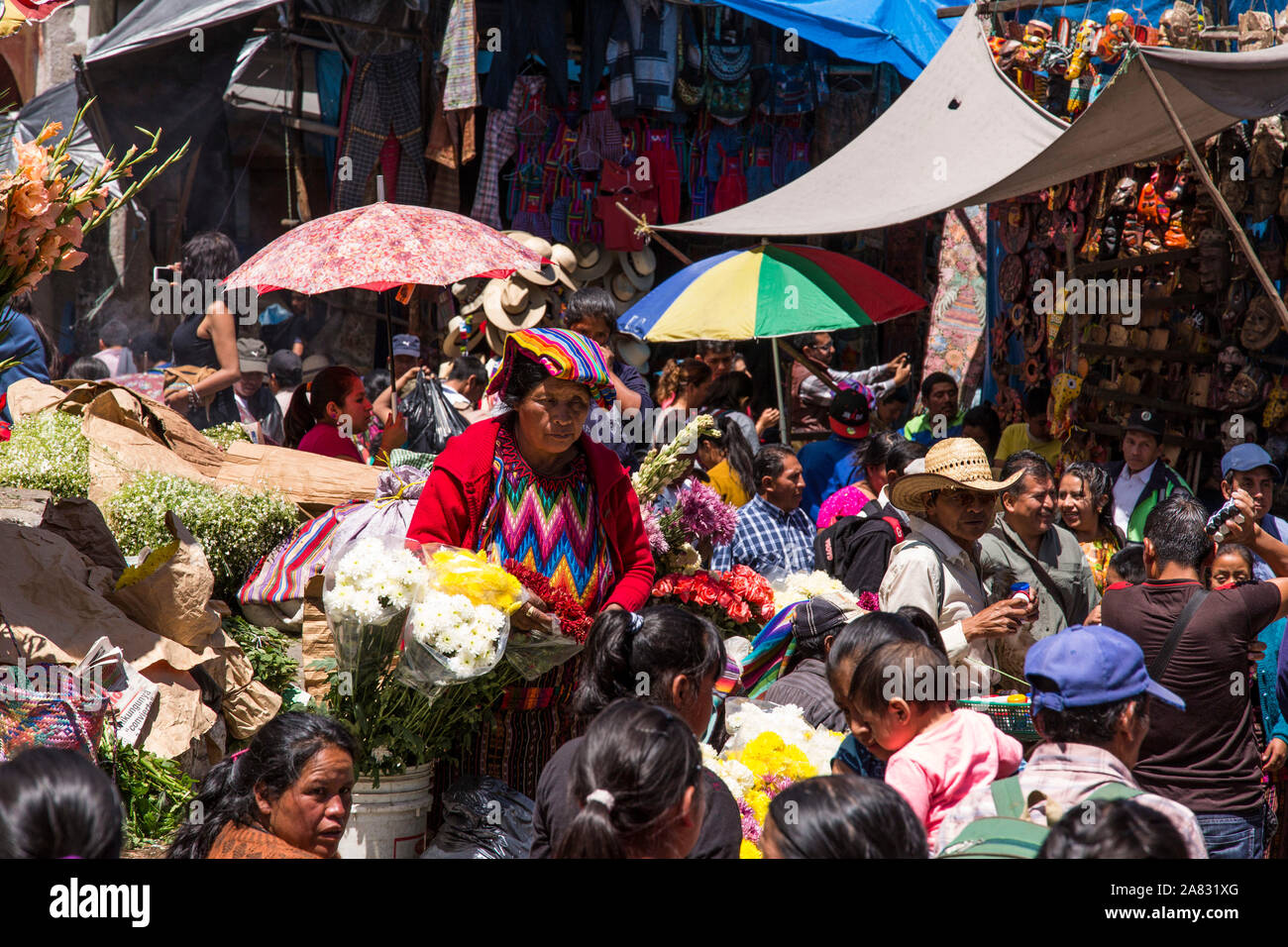 Una folla di gente che provengono dalle città vicine a partecipare al mercato di domenica a Chichicastenango, Guatemala. Una Quiche alle donne Maya vende fiori. Foto Stock