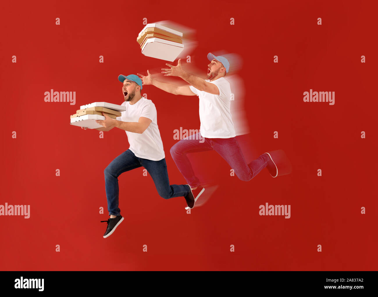Jumping corriere maschio con scatole per pizza sul colore di sfondo Foto Stock