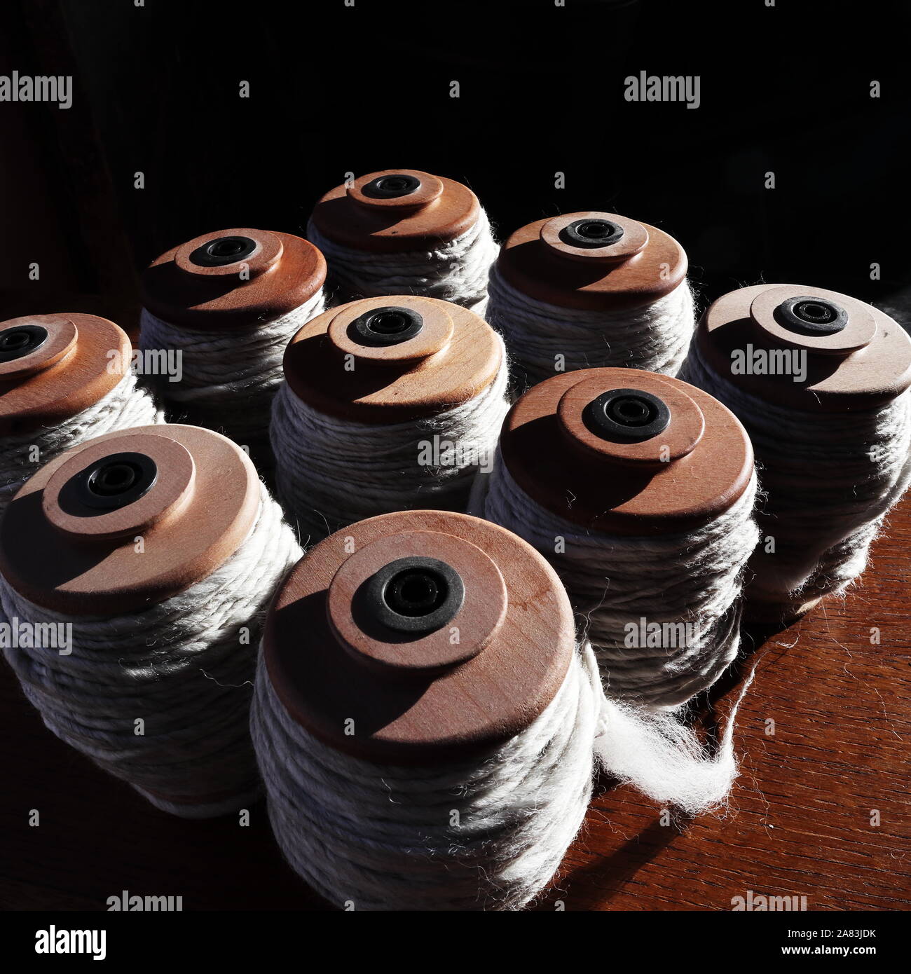 Nove ruota di filatura rocche riempito con handspun, grigio chiaro, il filo non colorato Foto Stock