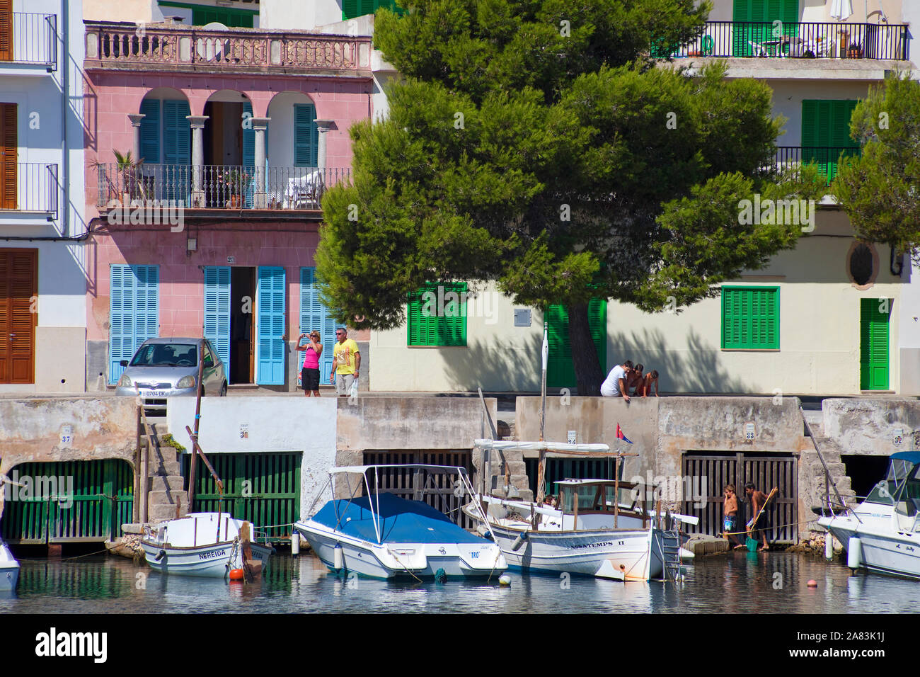Garage in barca sotto ex case di pesca e storico porto di Porto Colom, Maiorca, isole Baleari, Spagna Foto Stock