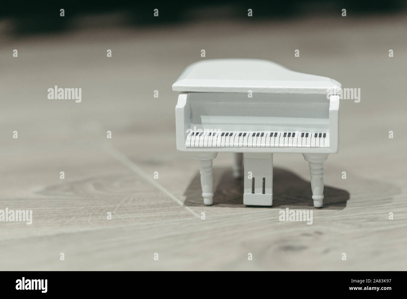 Piccolo giocattolo bianco musica per pianoforte macro ancora isolata su uno sfondo di legno Foto Stock