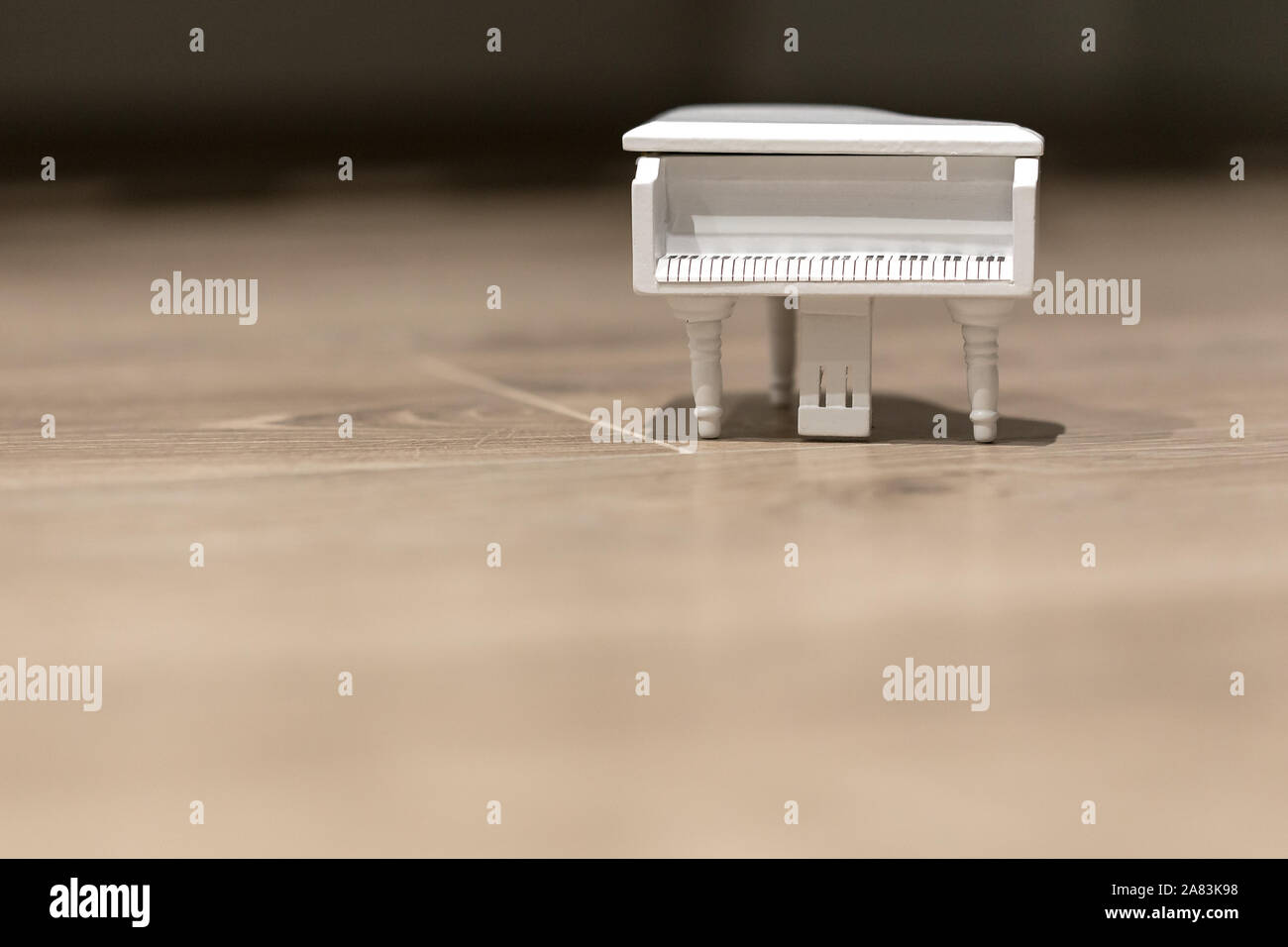 Piccolo giocattolo bianco musica per pianoforte macro ancora isolata su uno sfondo di legno Foto Stock