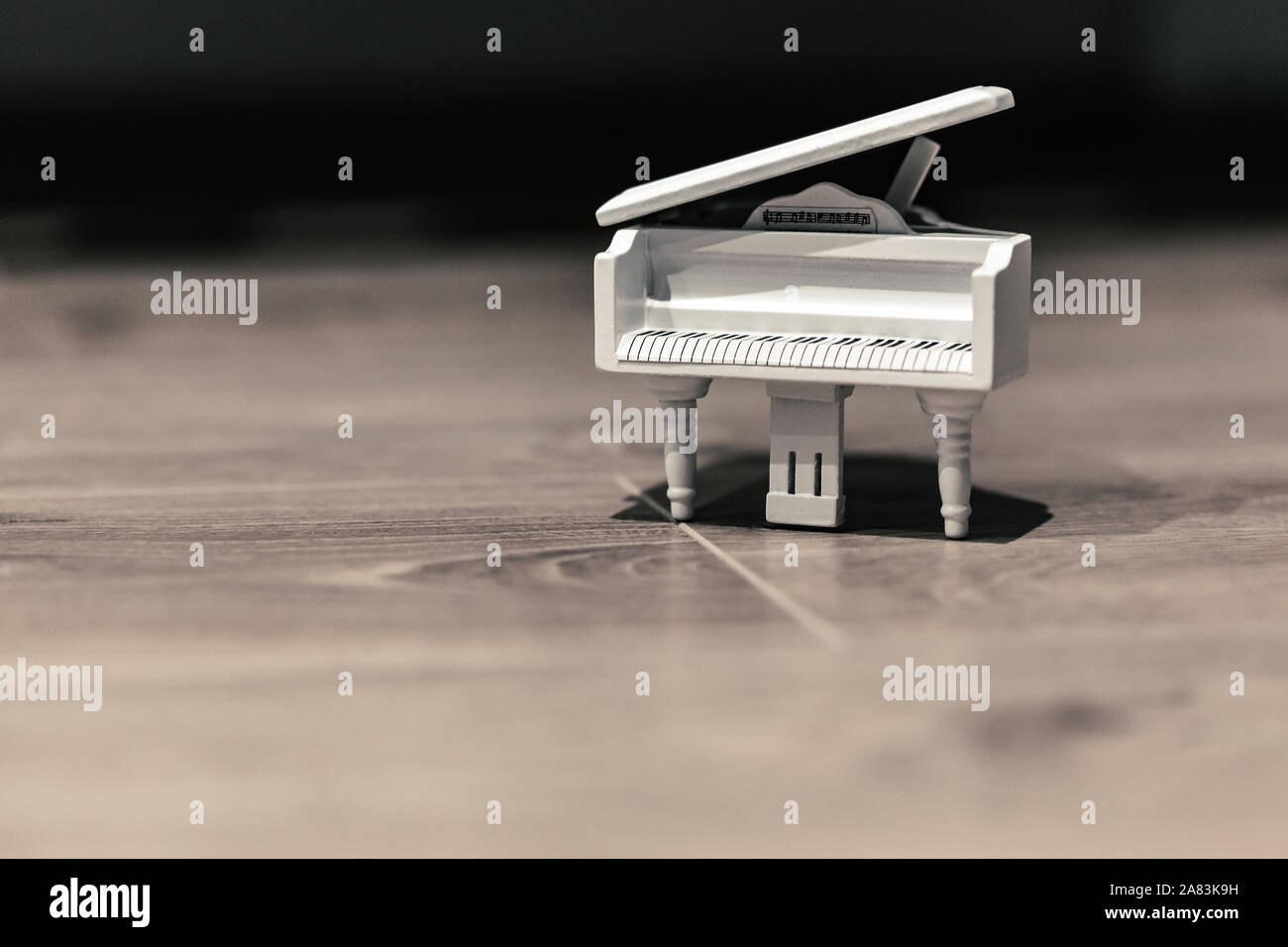 Piccolo giocattolo bianco musica per pianoforte macro ancora isolata su uno sfondo di legno Foto Stock