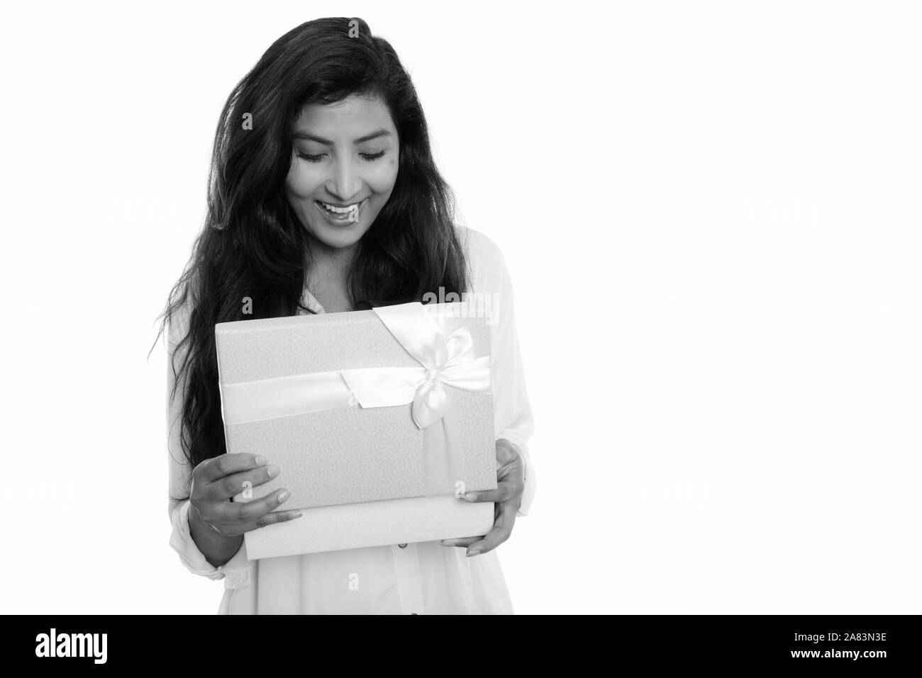Studio shot di giovani felici persiano di donna sorridente durante l'apertura della confezione regalo Foto Stock