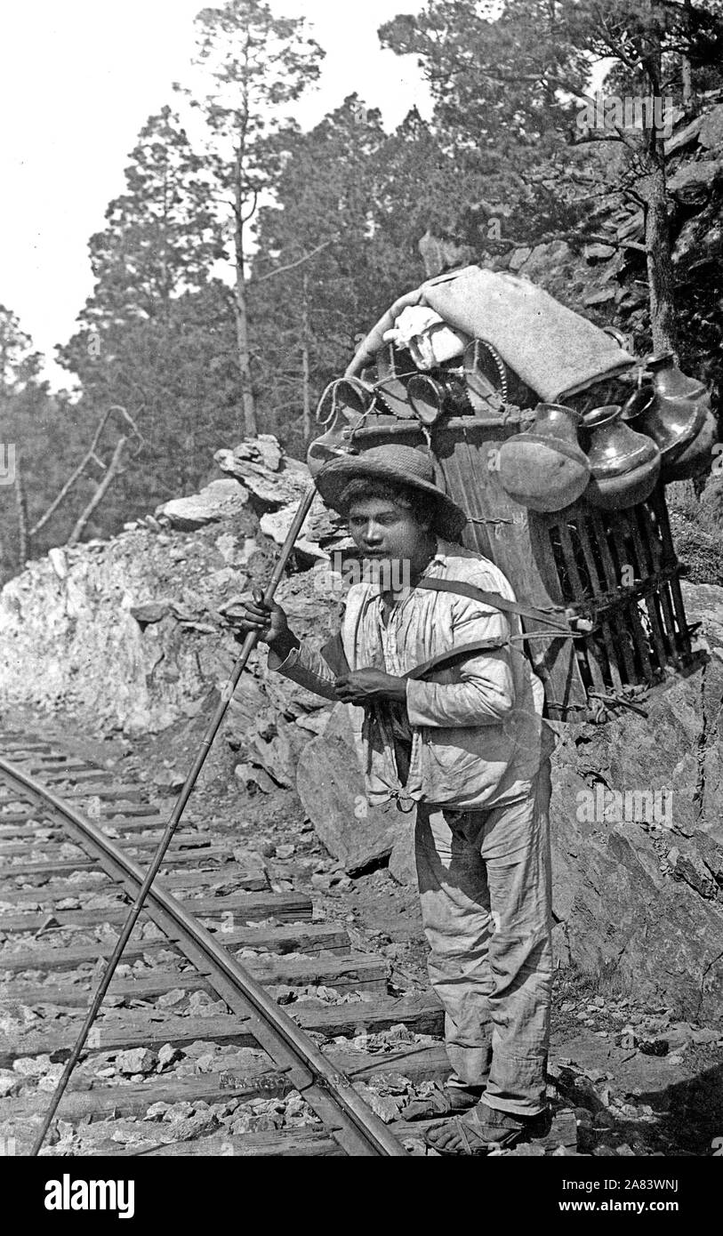 Uomo messicano che trasportano grandi bundle di pentole sul suo retro. 1890-1923 Foto Stock