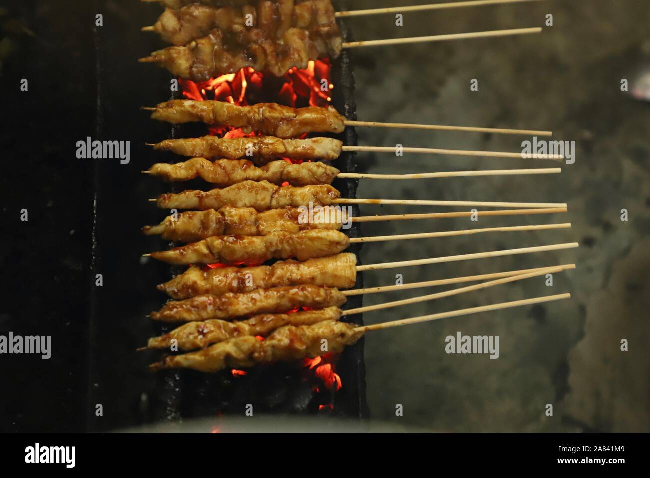 Pollo indonesiano saté essendo grigliate alla fiamma di carbone Foto Stock