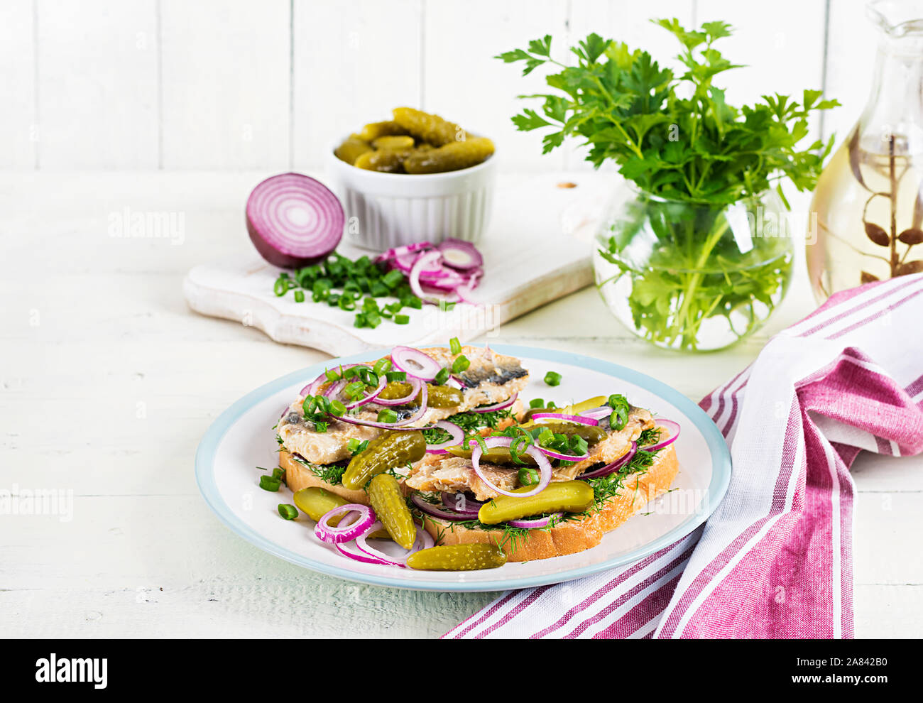 Olandese tradizionale panino con le aringhe e sottaceti cetrioli sul tavolo bianco. Smorrebrod. Foto Stock