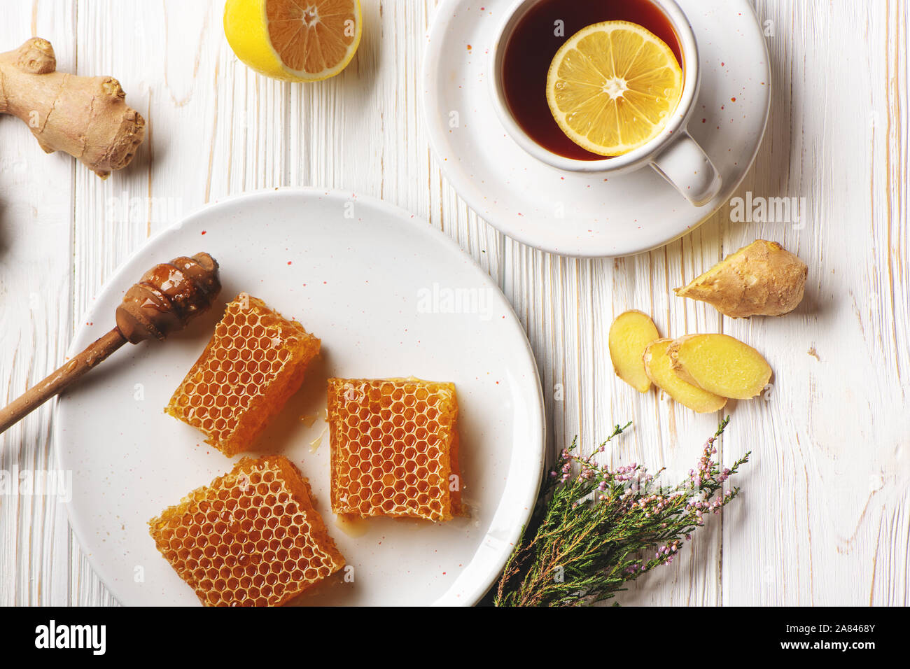 Favi con cucchiaio di miele, limone, lo zenzero e la tazza di tè bianco su sfondo di legno. Medicina Naturale concetto. Foto Stock