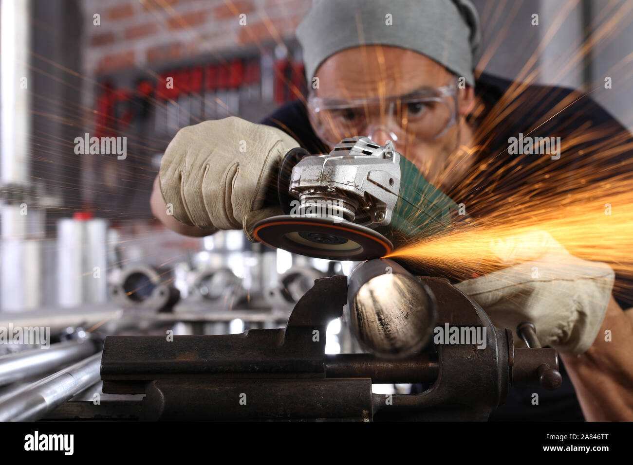 Uomo lavoro in officina di casa garage con smerigliatrice angolare, occhiali di protezione e guanti di costruzione, metallo levigatura fa scintille closeup, fai da te e del concetto di artigianato Foto Stock