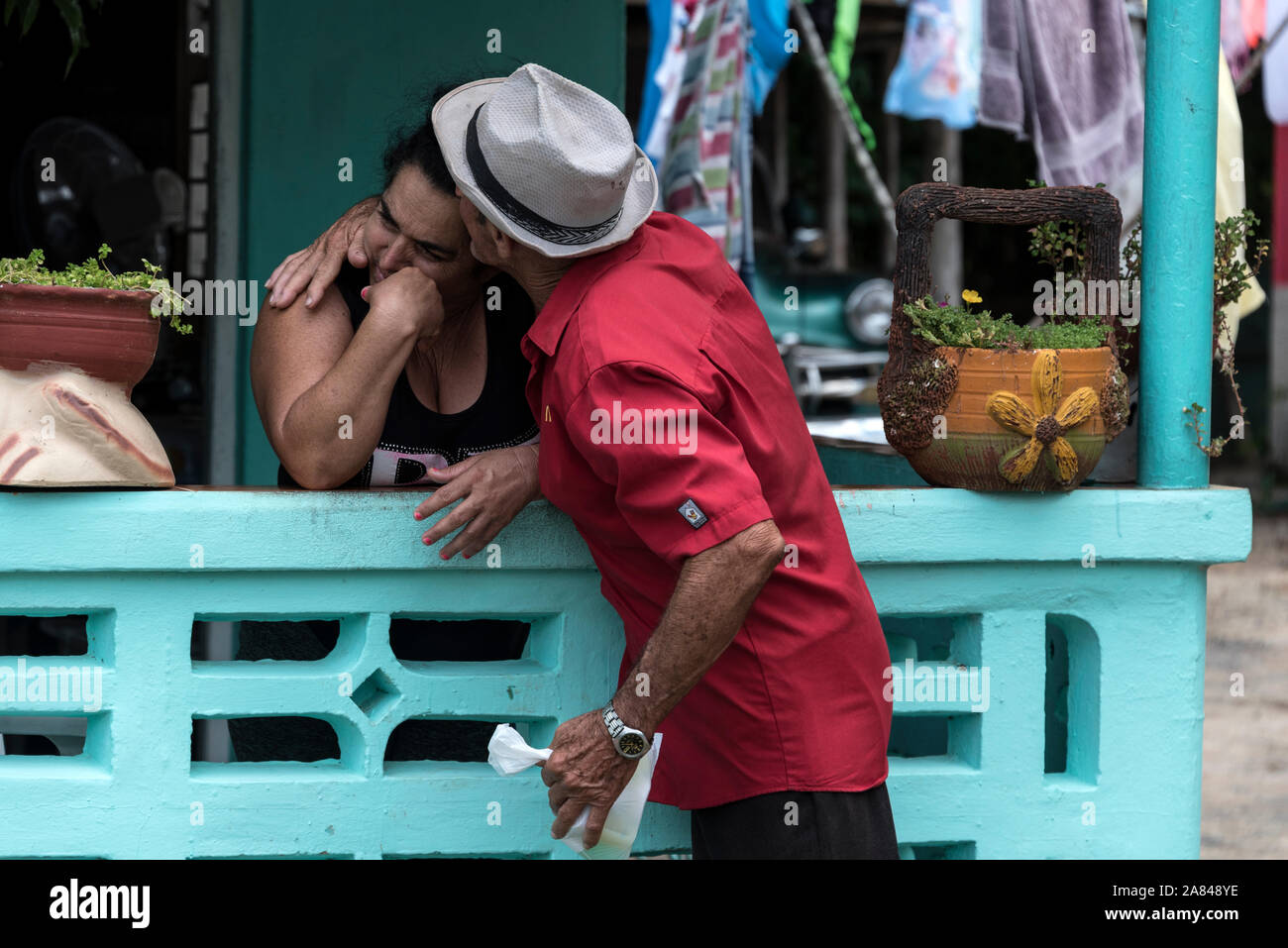 Una donna cubana riceve un abbraccio dal suo vicino di casa a casa sua in una fattoria di tabacco nella Valle de Vinales, Pinar del Río Provincia, Cuba Ovest Foto Stock