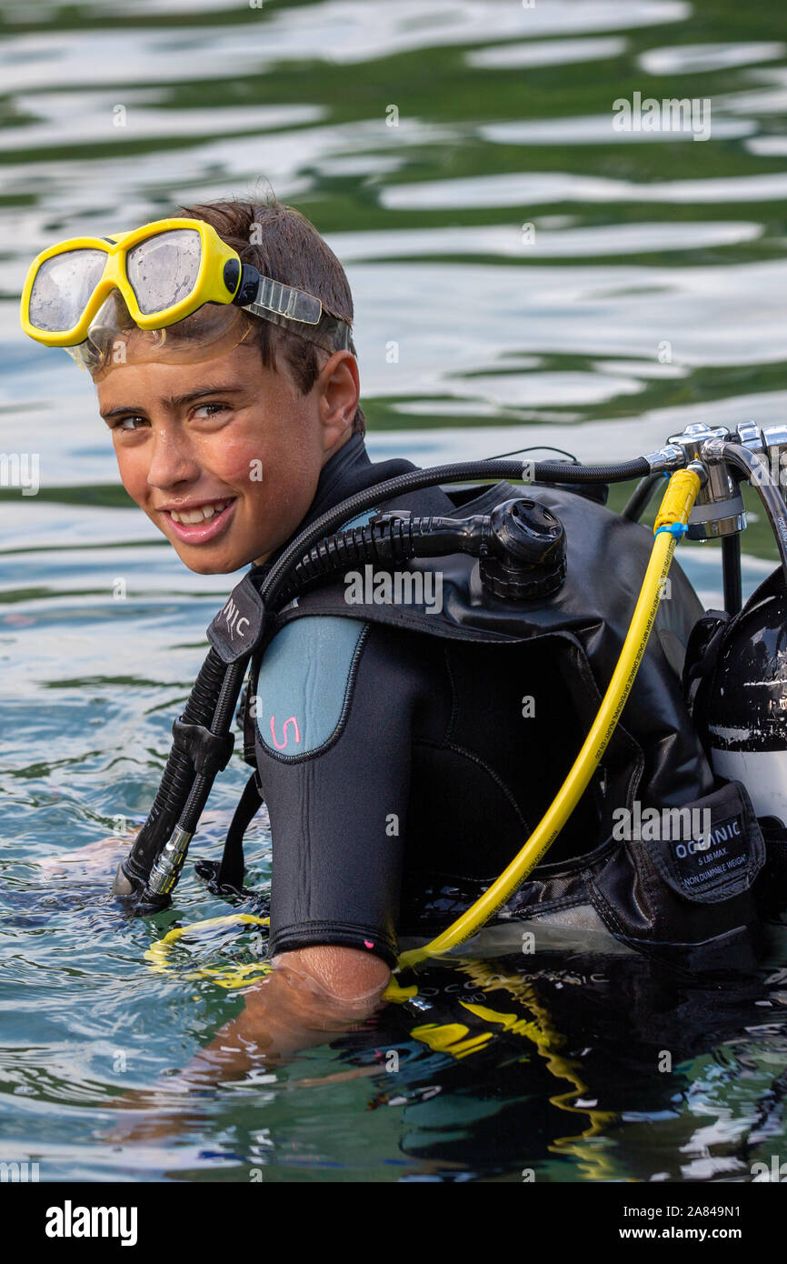Un giovane ragazzo che indossa la piena scuba diving outfit nell'acqua. Foto Stock